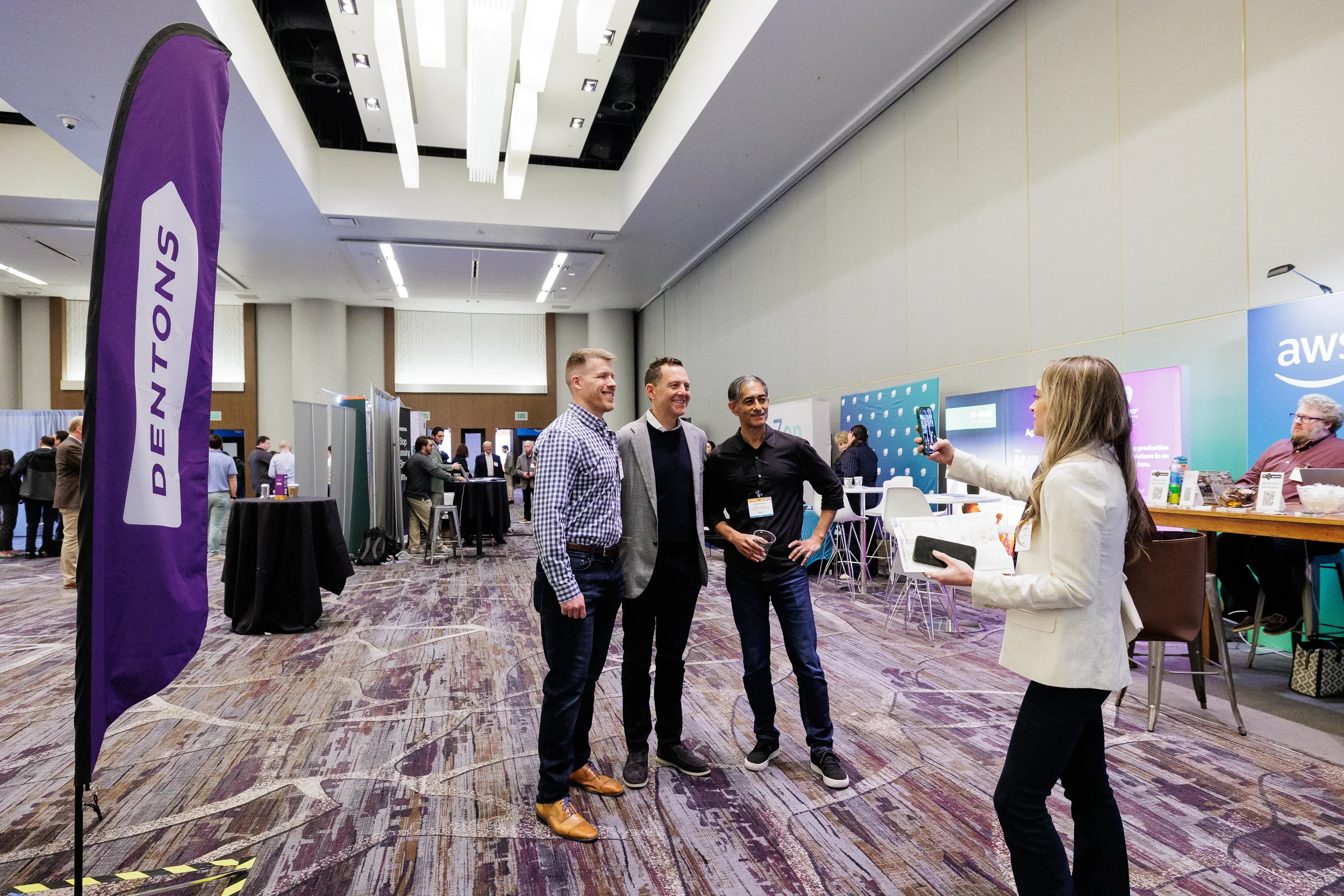 Three smiling badged attendees pose for photo on Orlando corporate conference trade show floor