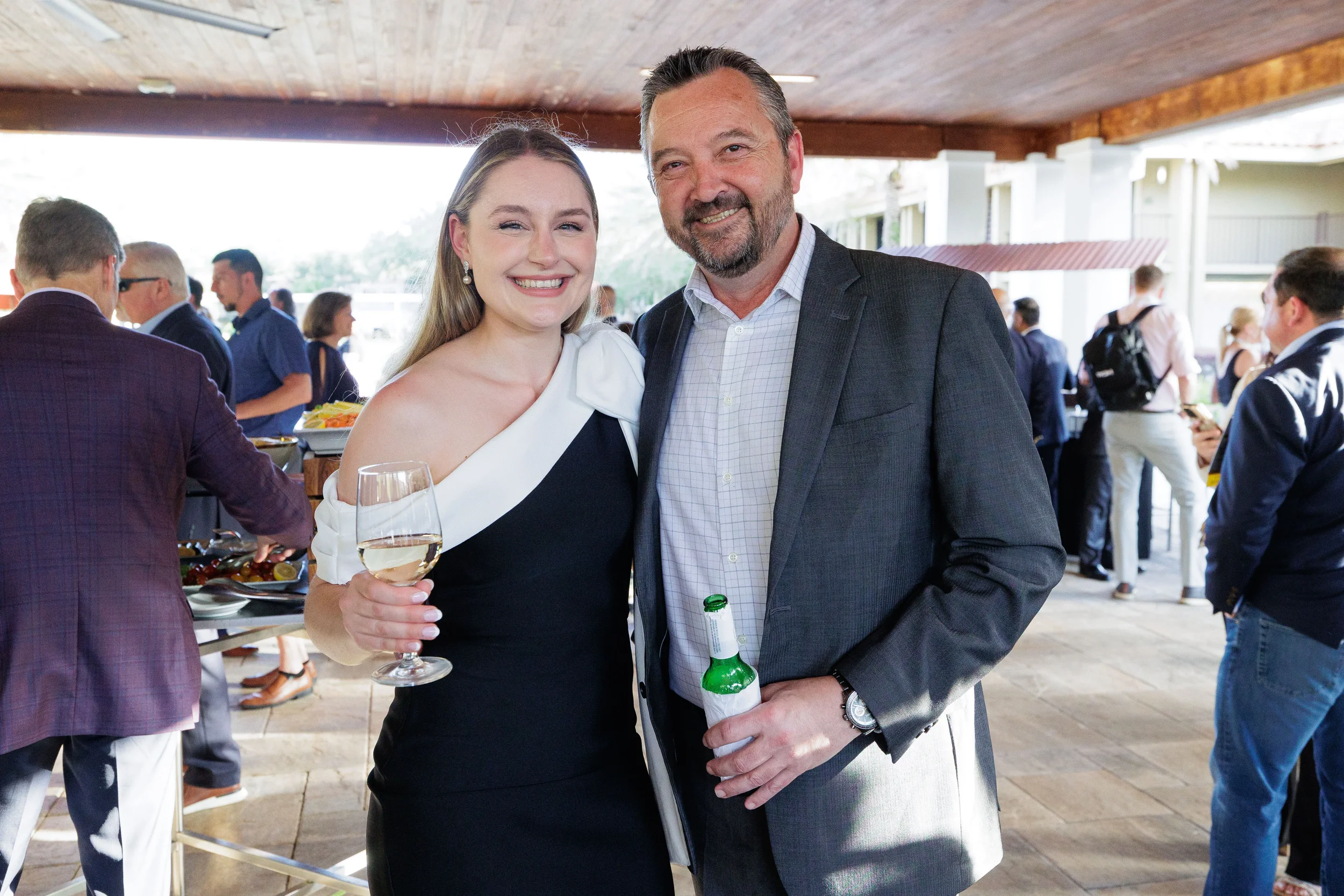 Two attendees pose and smile with drinks at outdoor pavilion reception at Orlando industry conference
