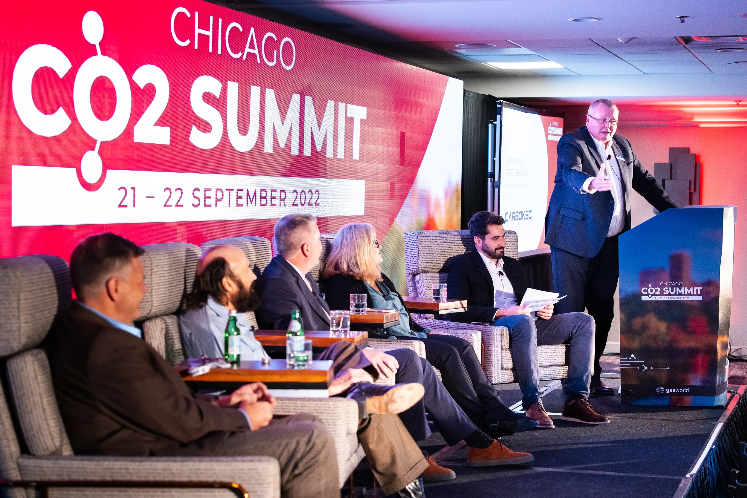 Speaker addresses panelists from podium during industry panel discussion at Orlando conference