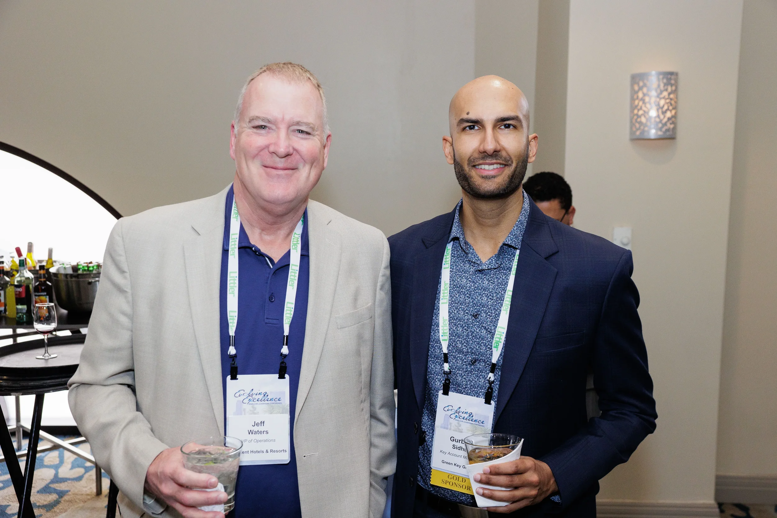 Two male attendees with lanyards smile together during networking reception at Orlando corporate event