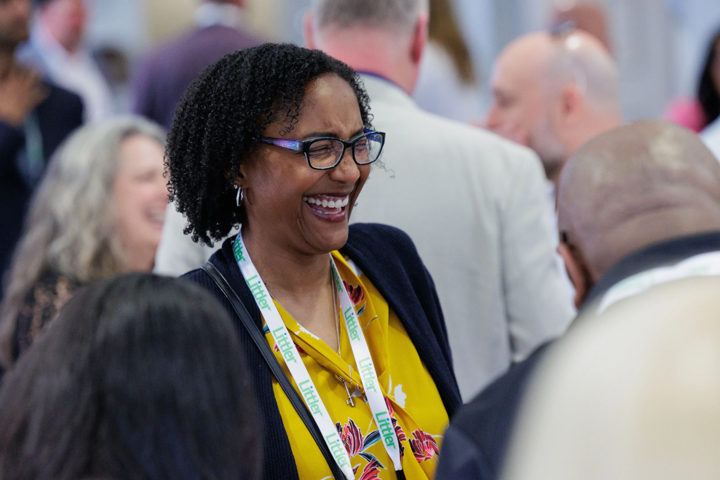 Female attendee with lanyard laughs warmly during networking reception at Chicago corporate conference