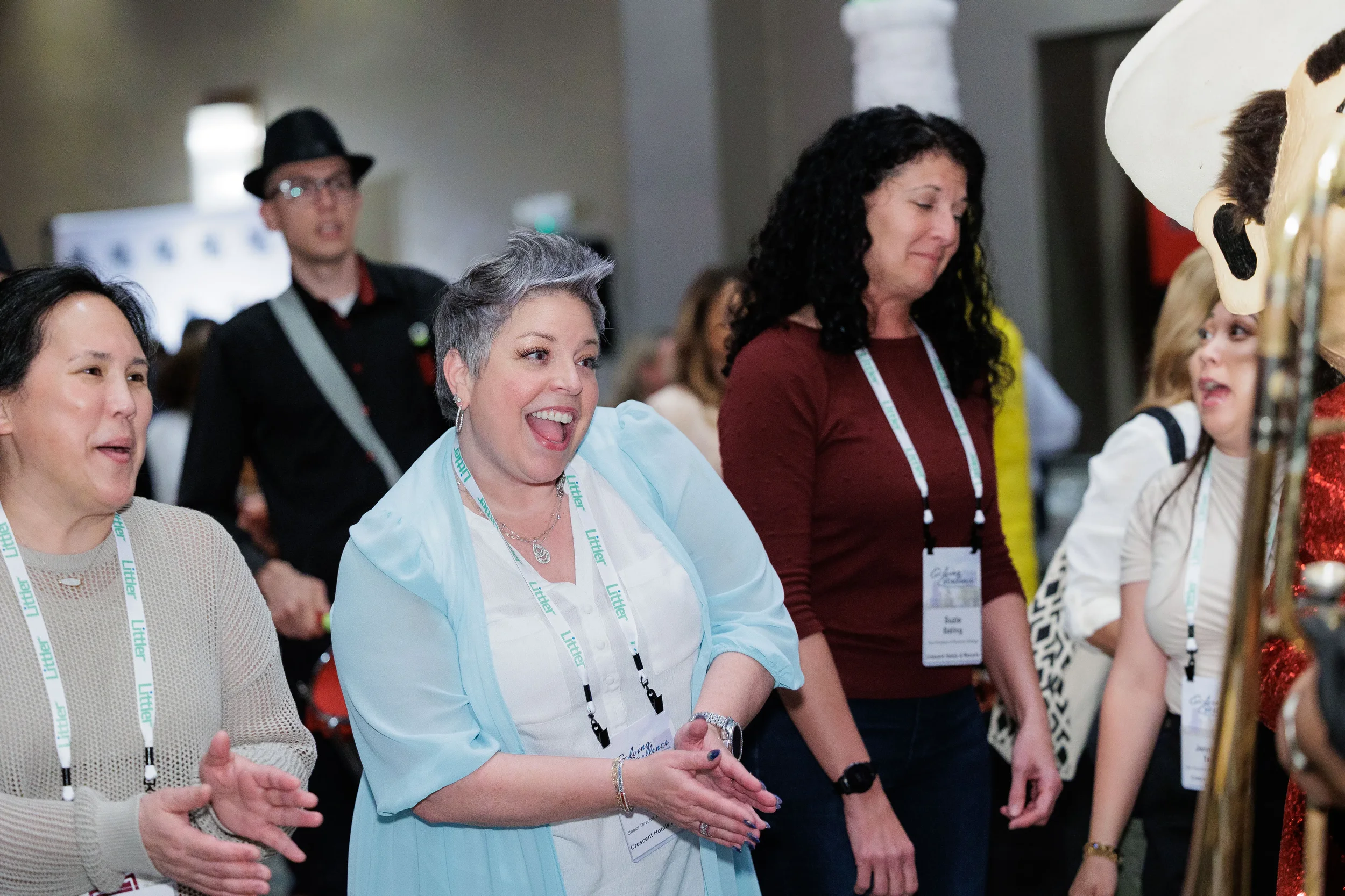 Excited attendees with lanyards react to mascot character on Orlando corporate conference expo floor