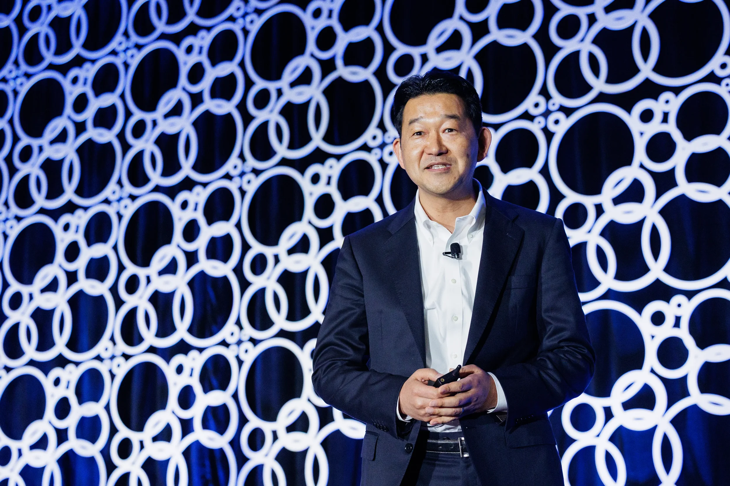 Speaker presents on stage with illuminated circular backdrop at Orlando corporate conference