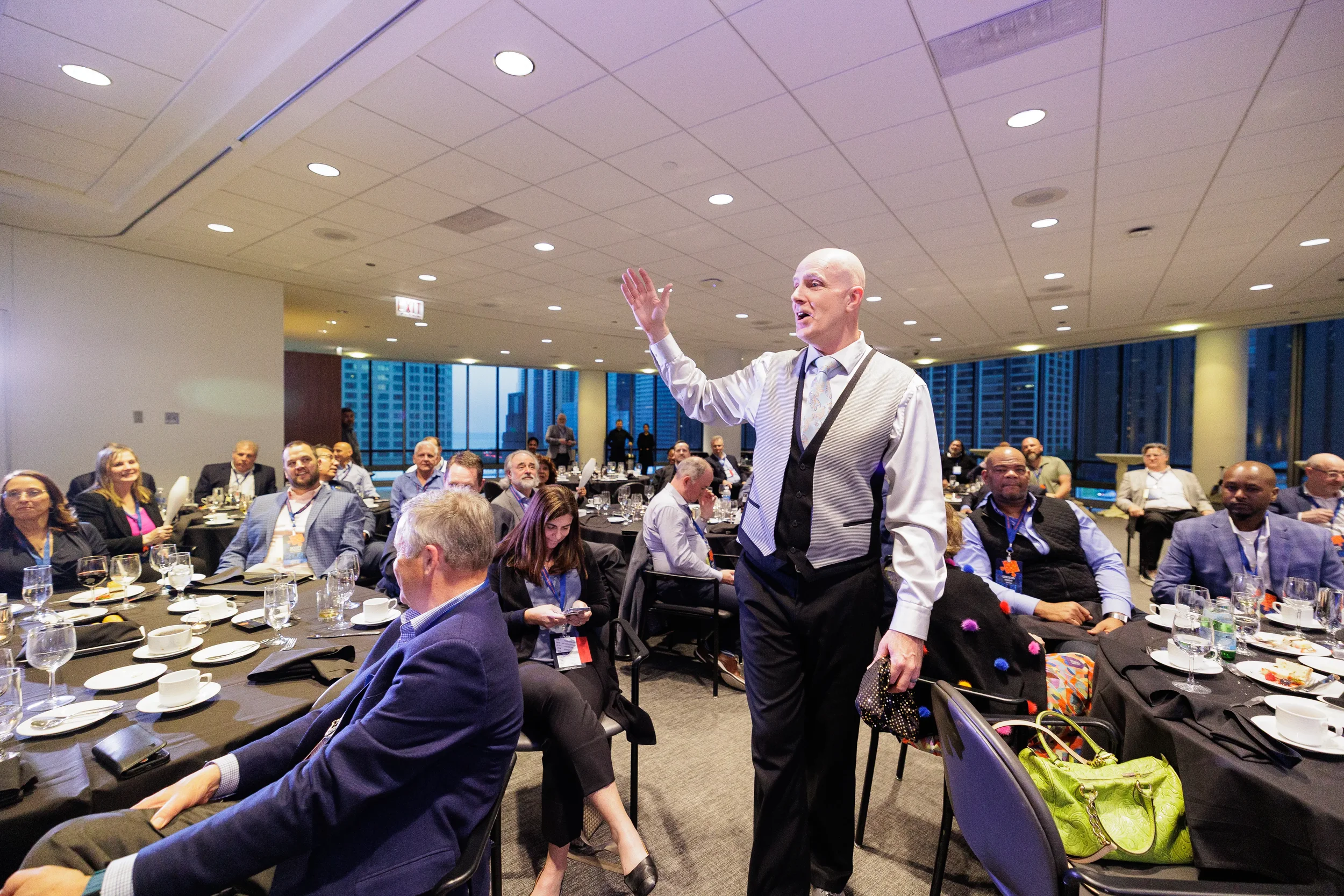 Entertainer addresses seated audience at round tables during Chicago corporate conference gala dinner