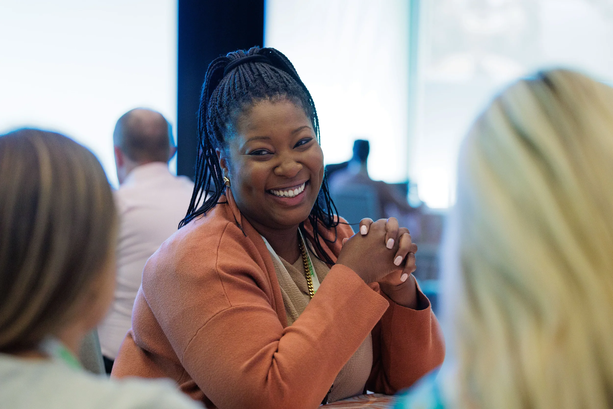 Female attendee smiles warmly with clasped hands during table discussion at Orlando corporate conference
