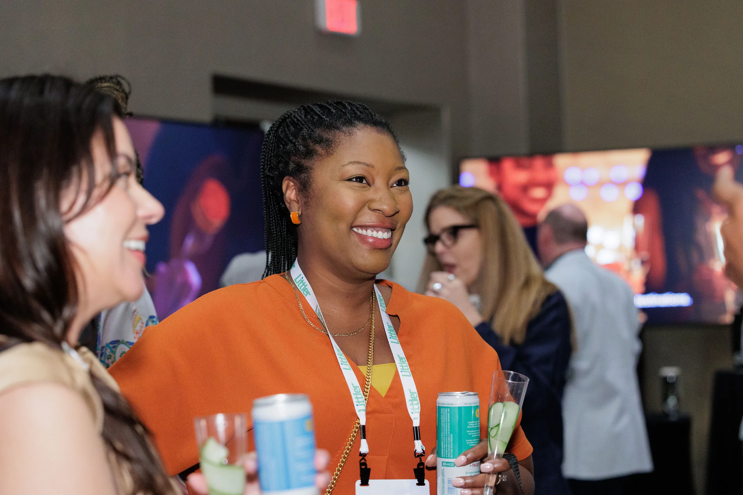 Attendee with lanyard smiles and holds drinks while networking at Chicago corporate conference reception