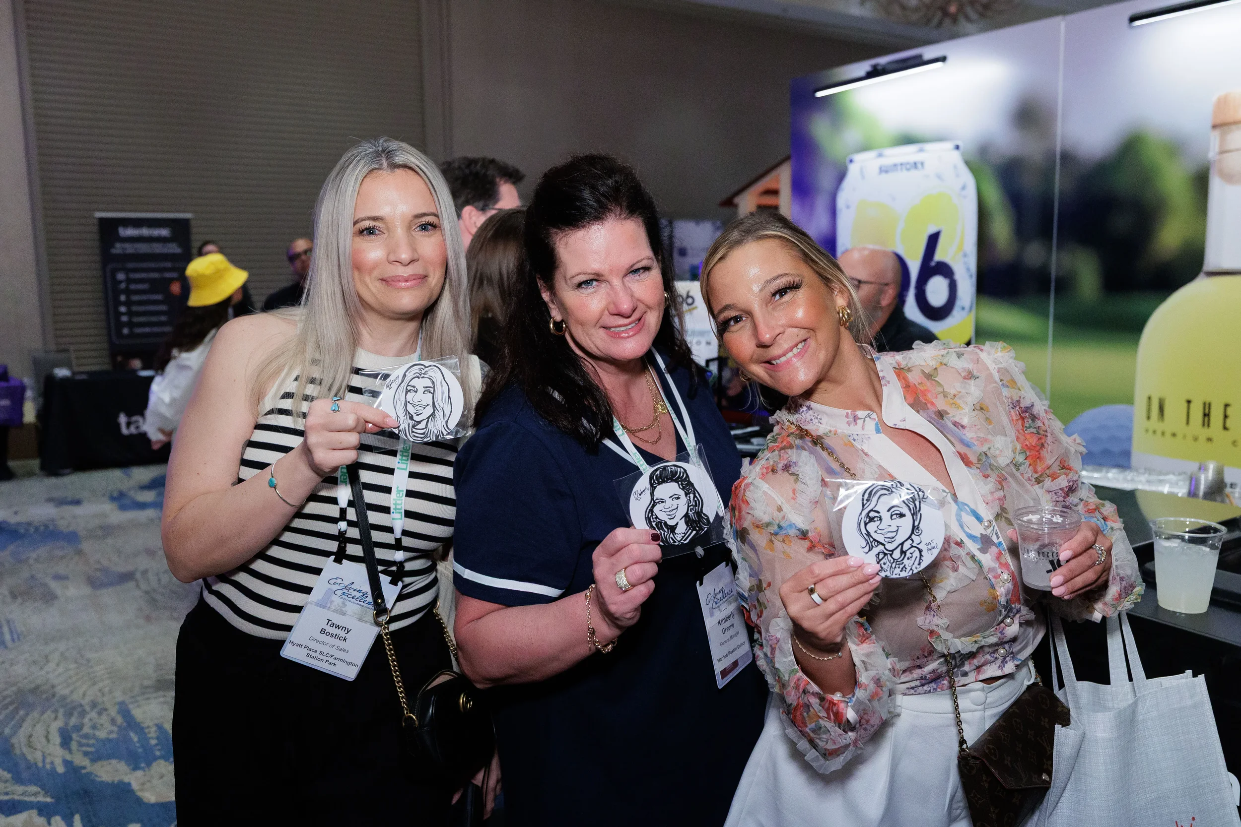 Three female attendees with lanyards hold caricature portraits at Chicago corporate conference reception