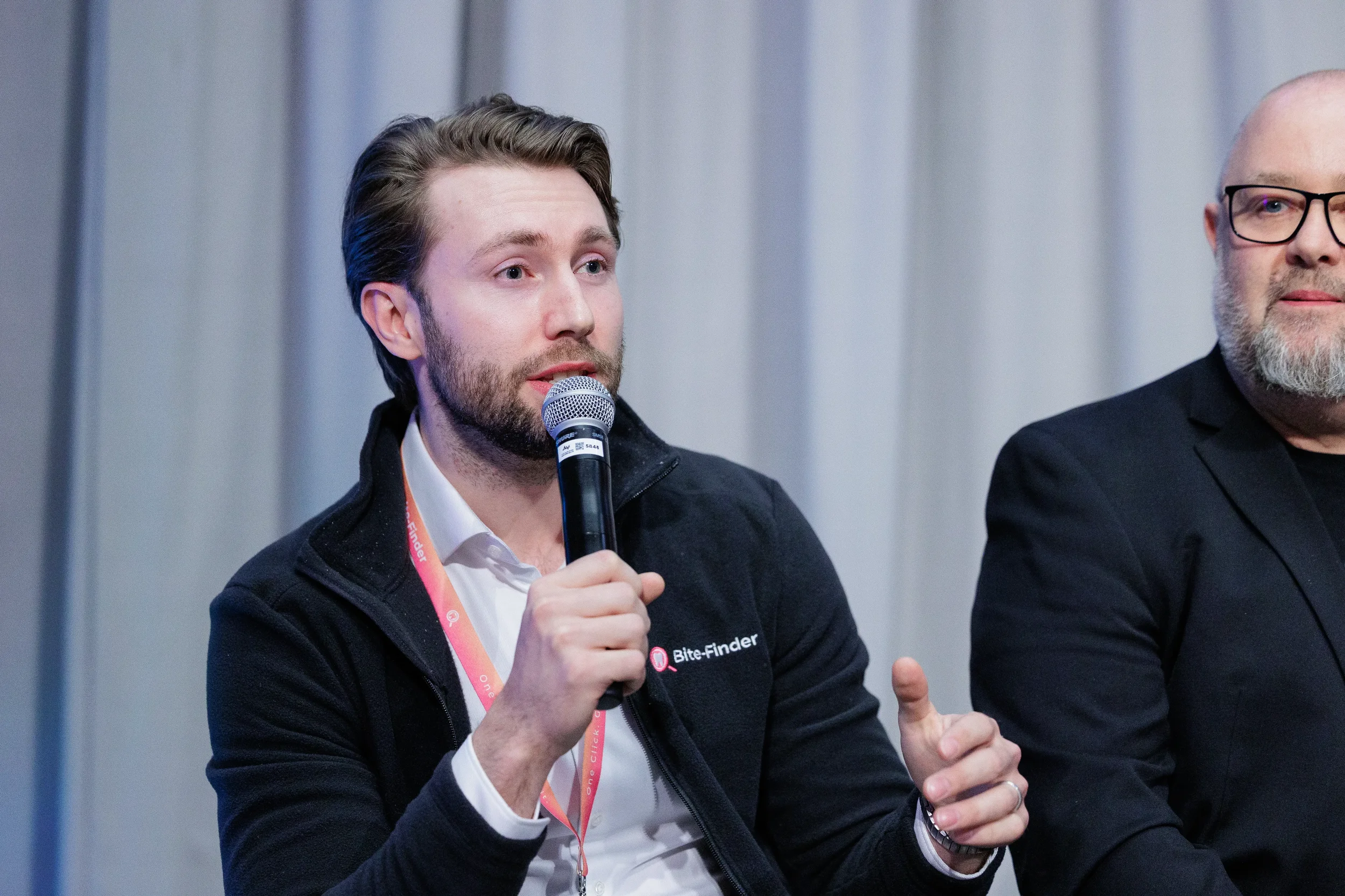 Lanyard-wearing panelist speaks into microphone during seated panel discussion at Chicago industry conference