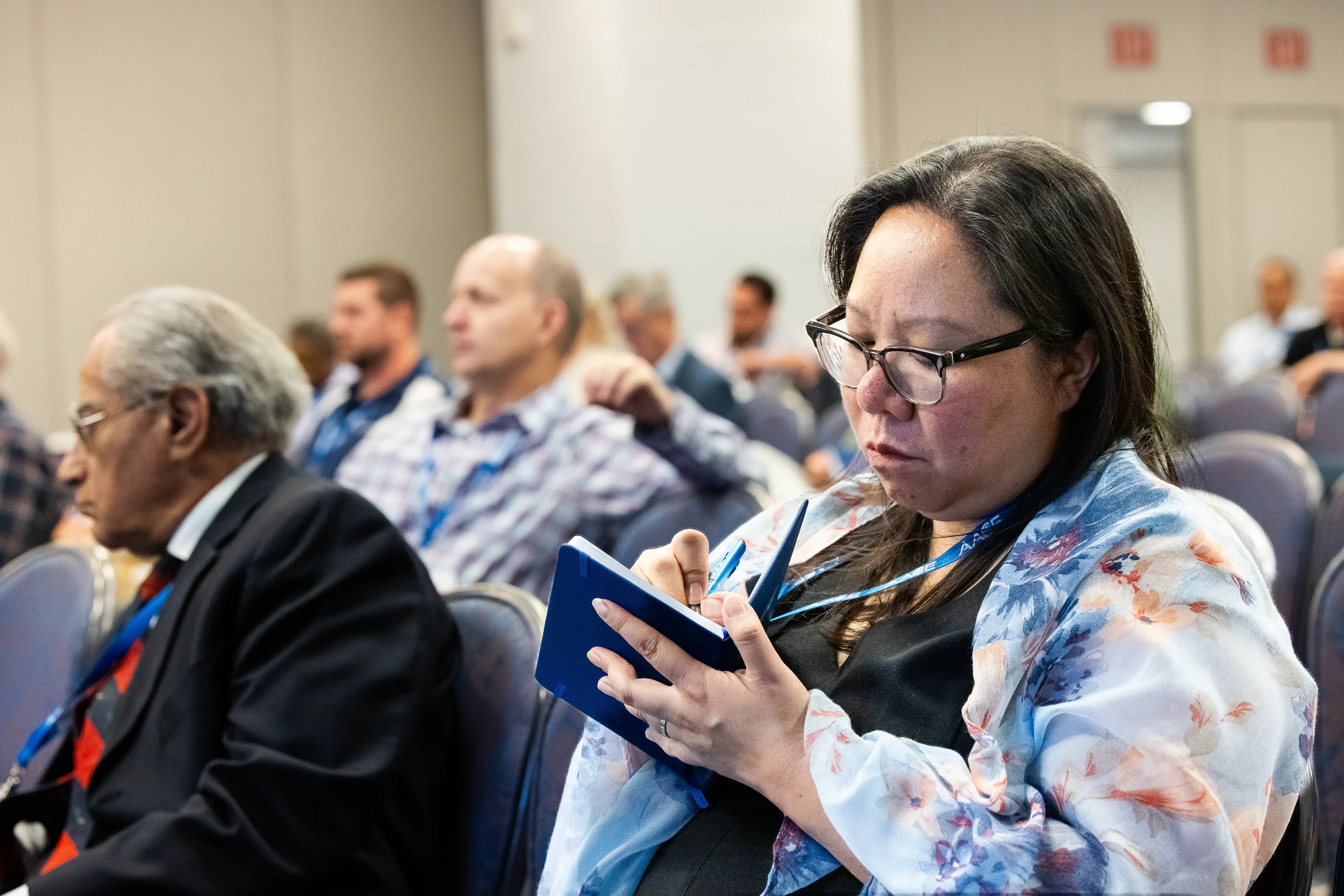 Attendee writes notes in notebook while seated during session at Orlando industry conference