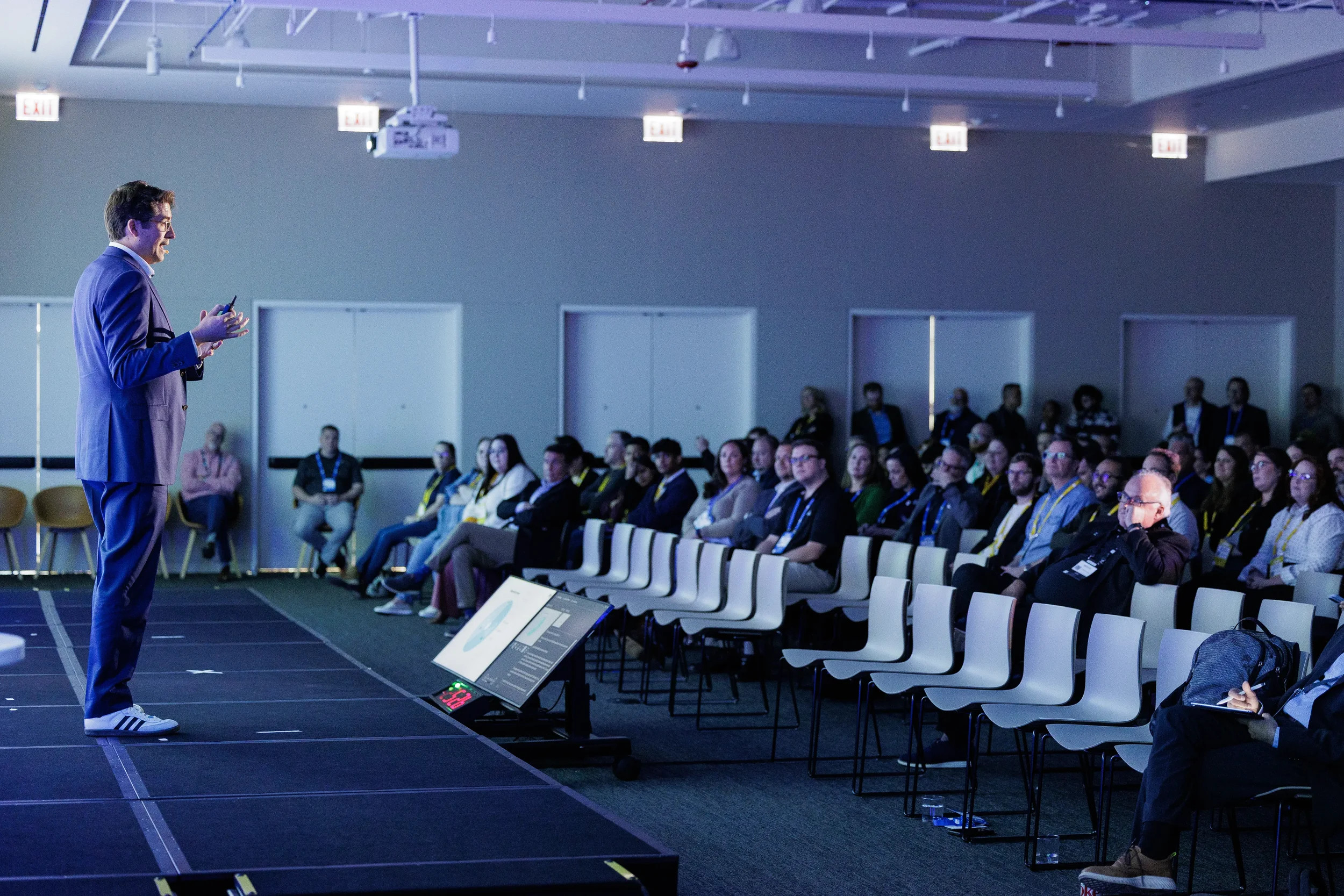 Speaker presents to seated audience in dimly lit session room at Chicago industry conference