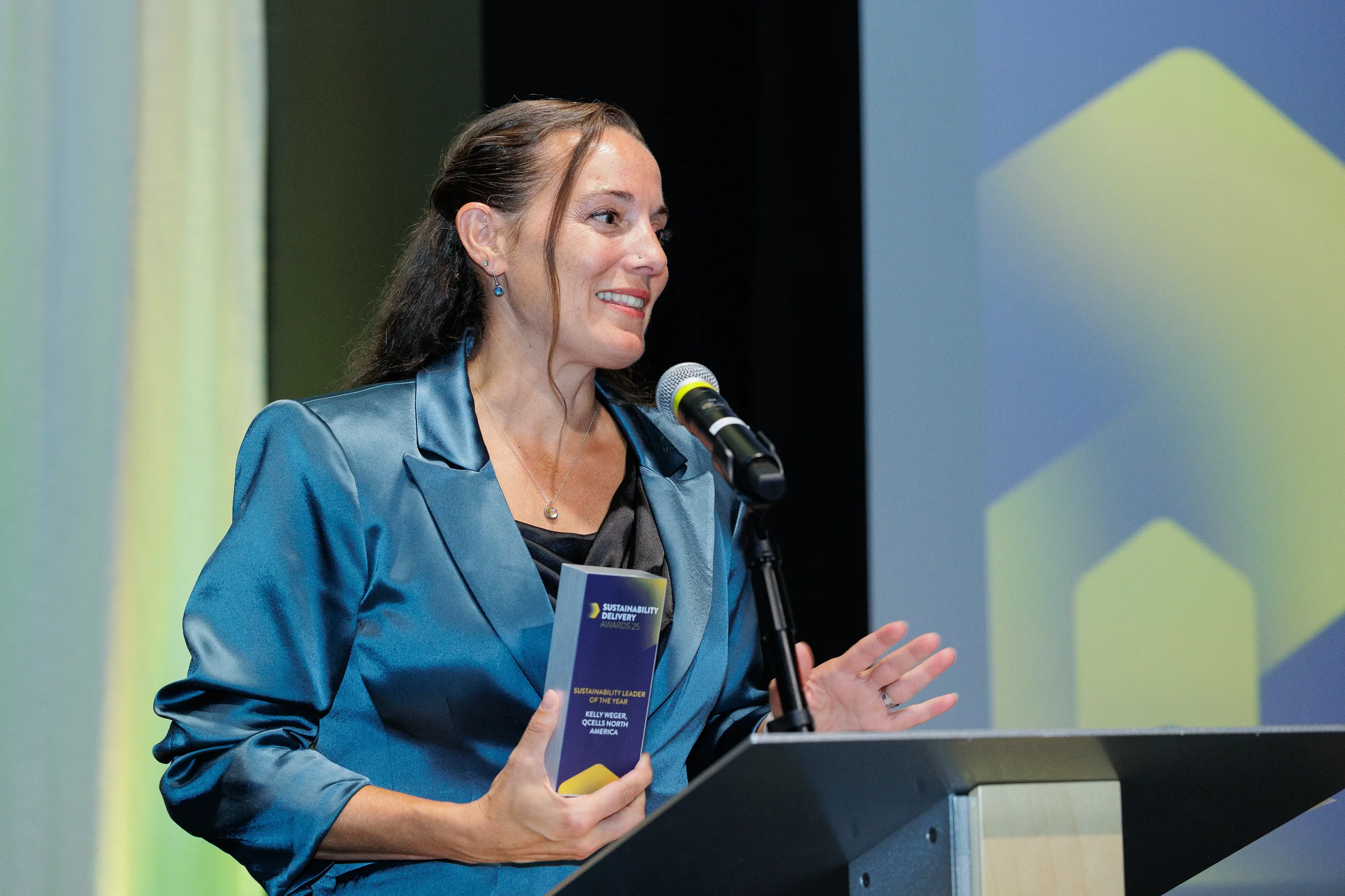 Speaker gestures from podium while holding award trophy at Chicago industry conference ceremony