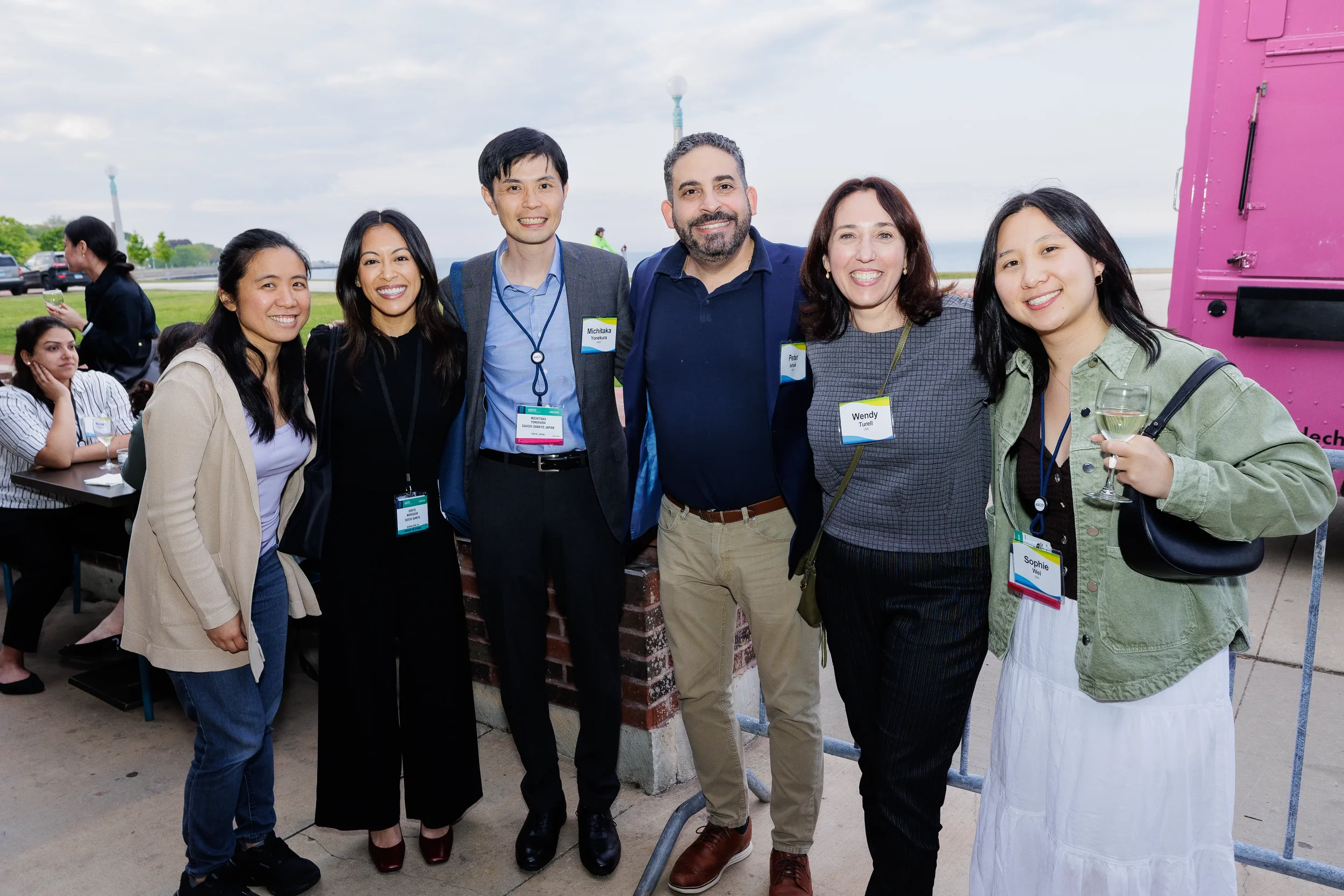 Six attendees pose together at outdoor lakefront reception during Chicago networking event