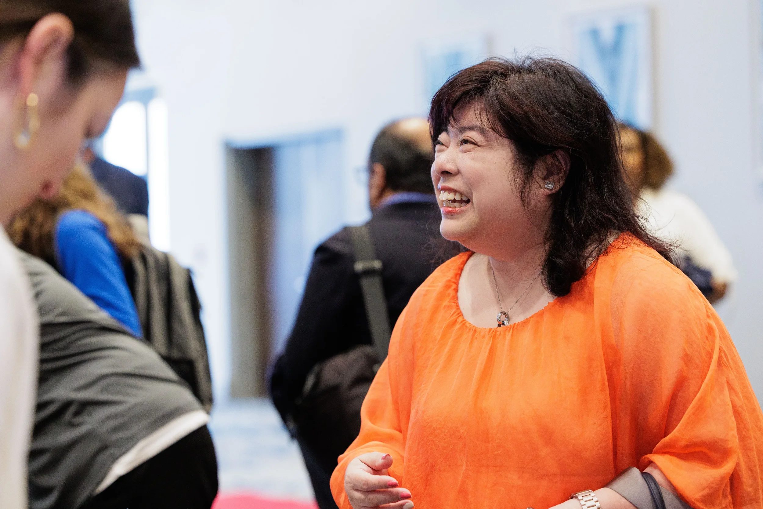 Smiling attendee in orange top laughs during networking reception at Chicago corporate conference