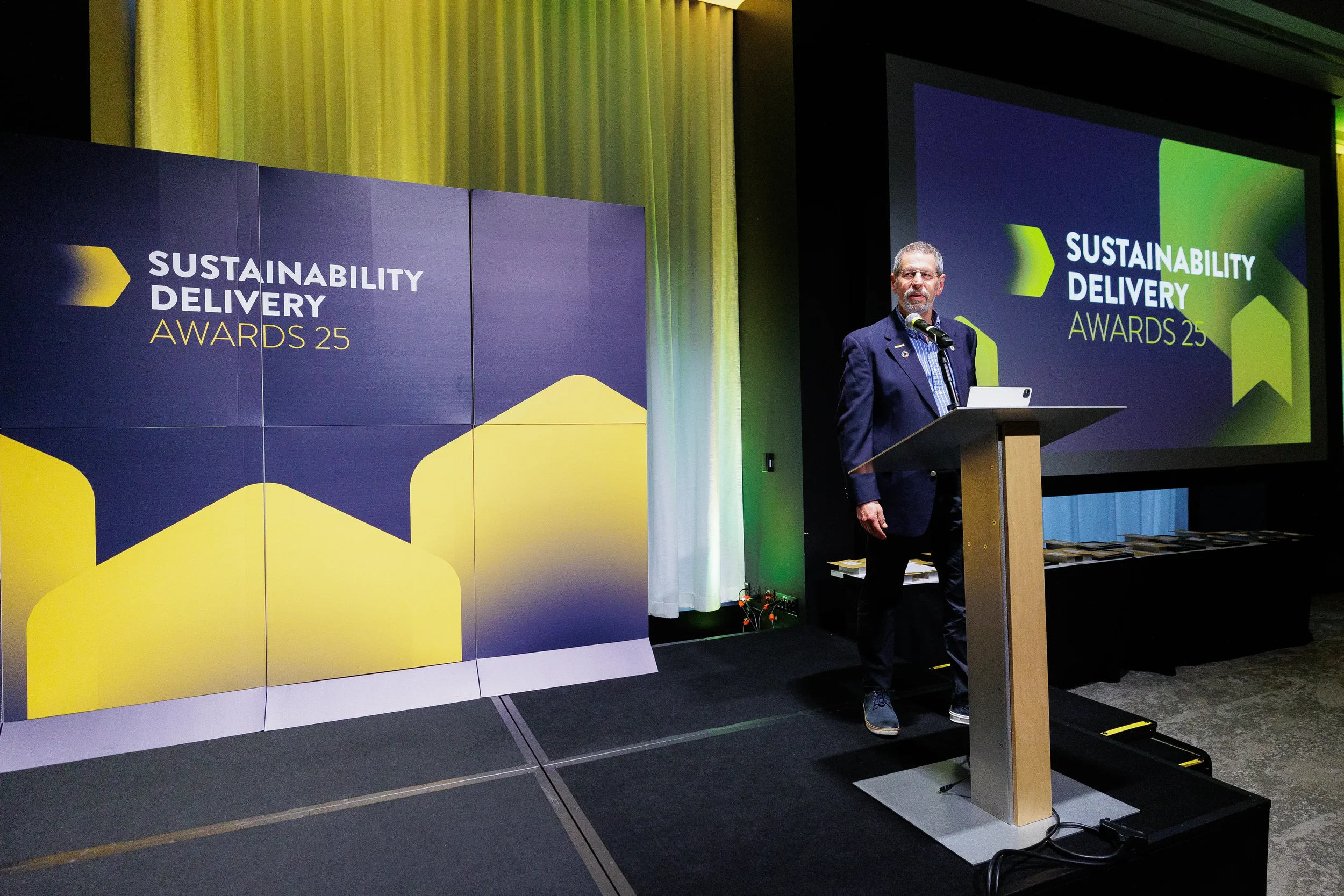 Speaker addresses audience from podium on stage with branded backdrop at Chicago awards ceremony