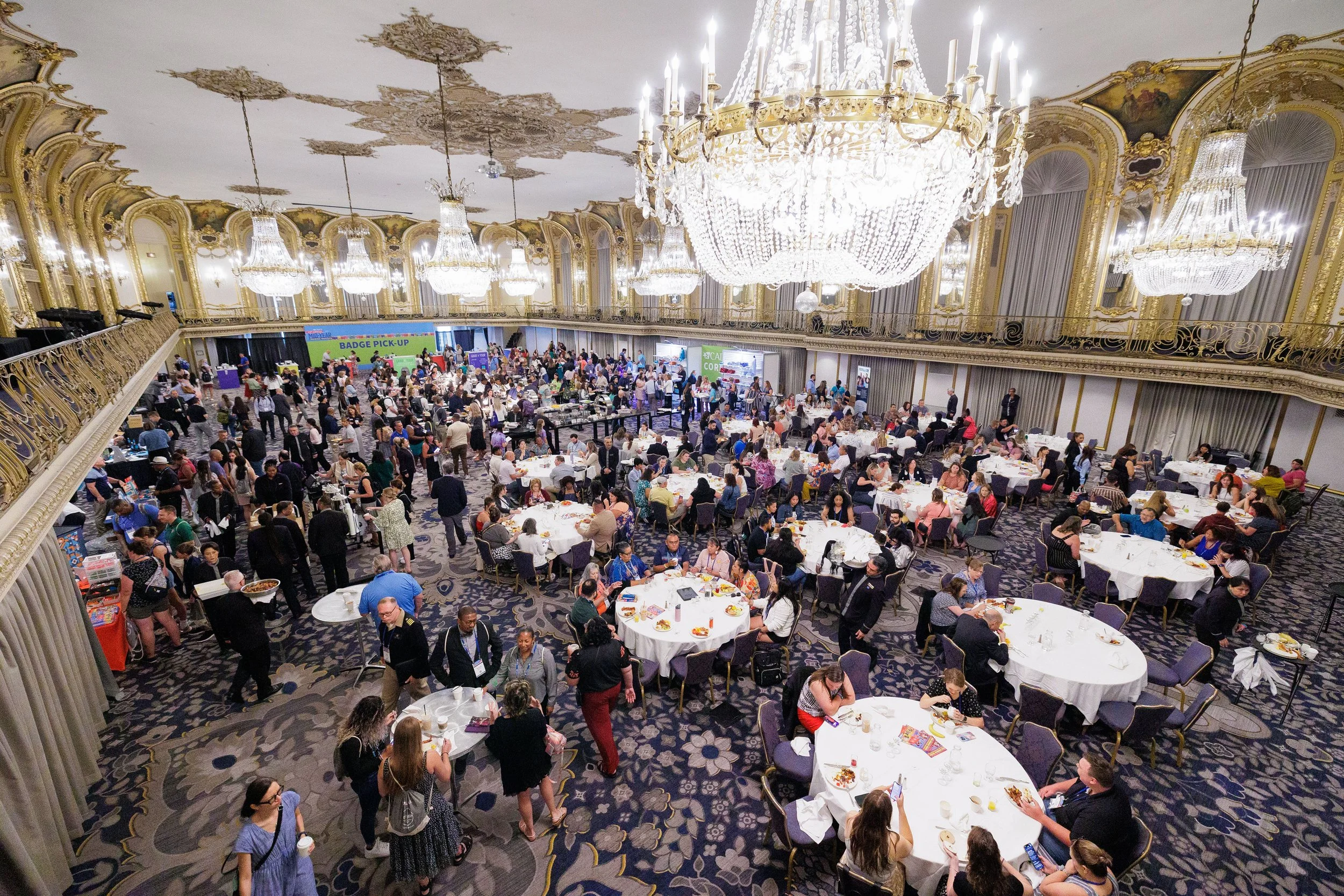 Conference attendees networking and dining in ornate grand ballroom with crystal chandeliers at Orlando corporate event