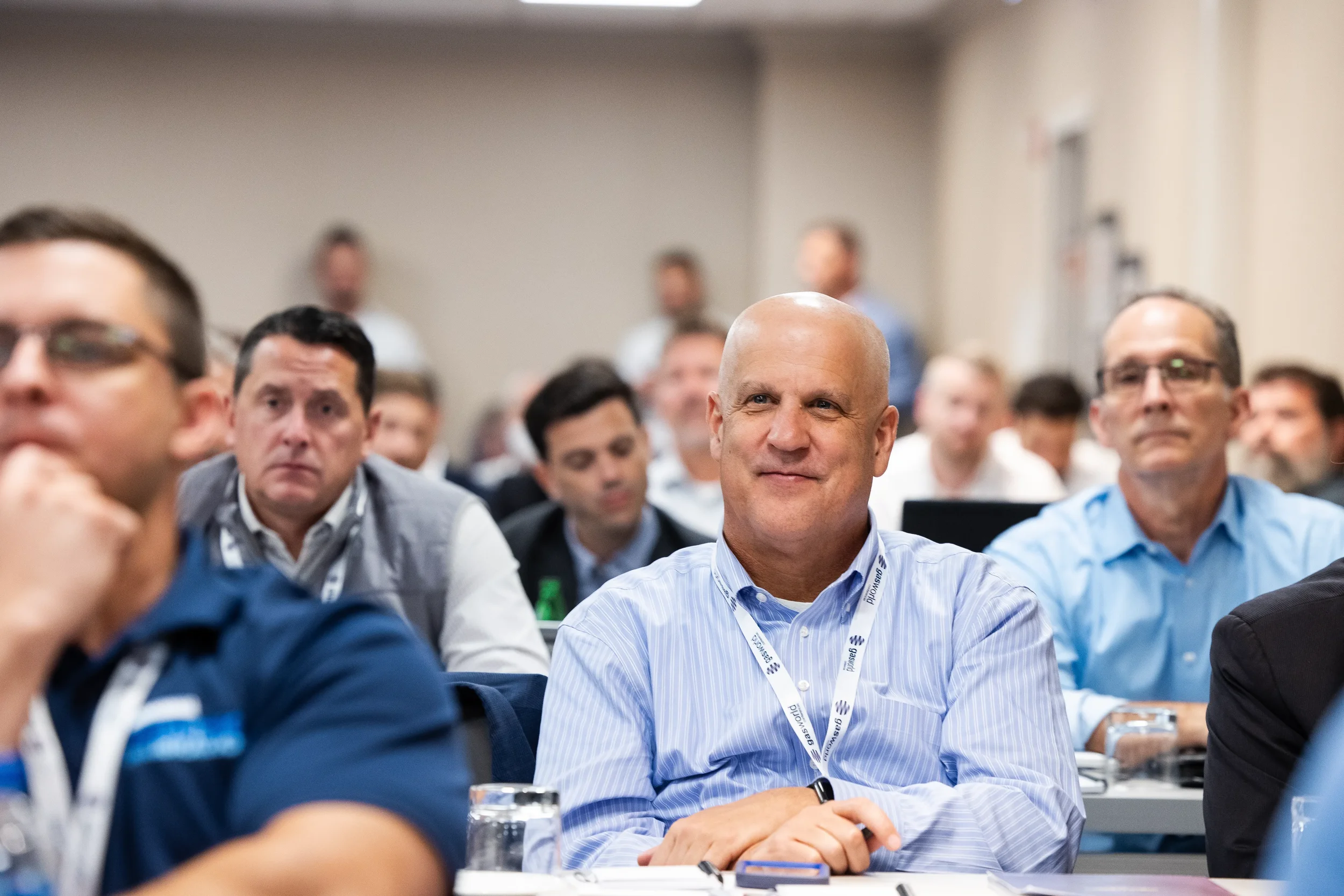 Attendee wearing conference lanyard listens attentively in audience at Orlando industry conference event