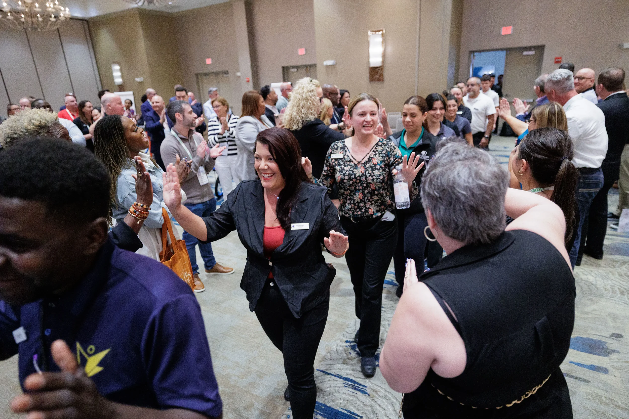 Attendees high-five and cheer during lively group activity in ballroom at Chicago corporate event