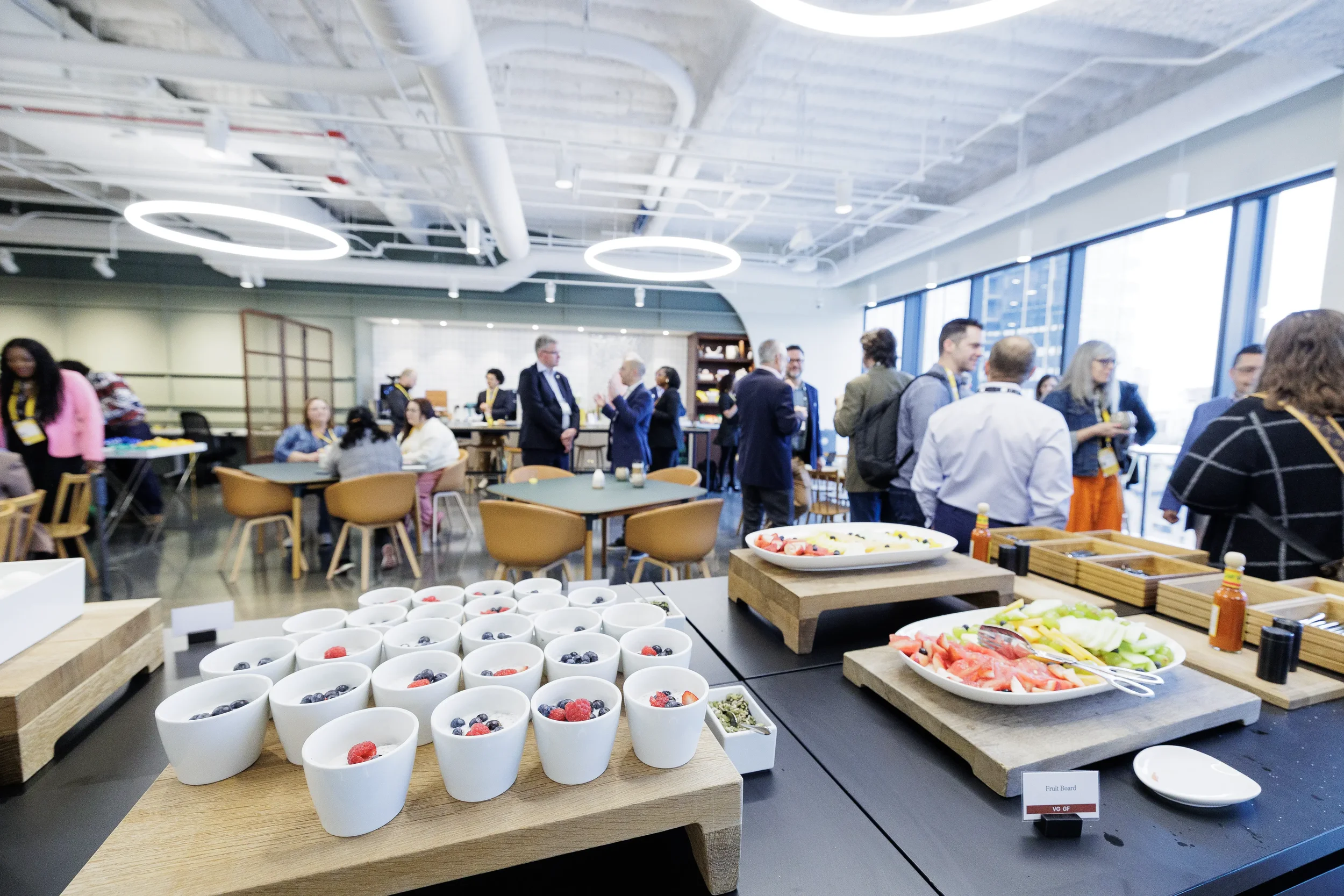 Breakfast buffet with yogurt cups and fruit boards as attendees mingle at Orlando corporate event