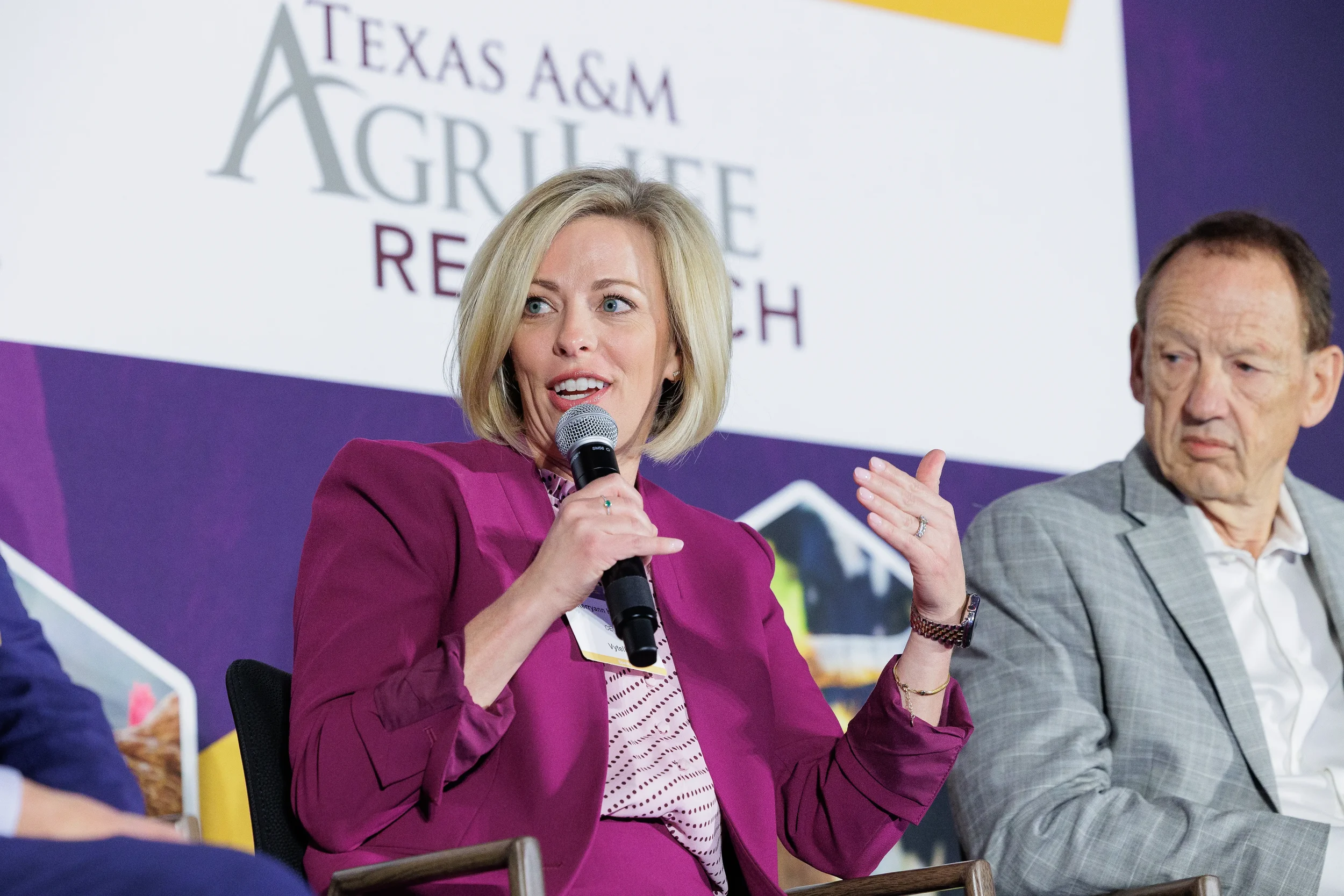 Panelist gestures while speaking into microphone during seated discussion at Chicago summit