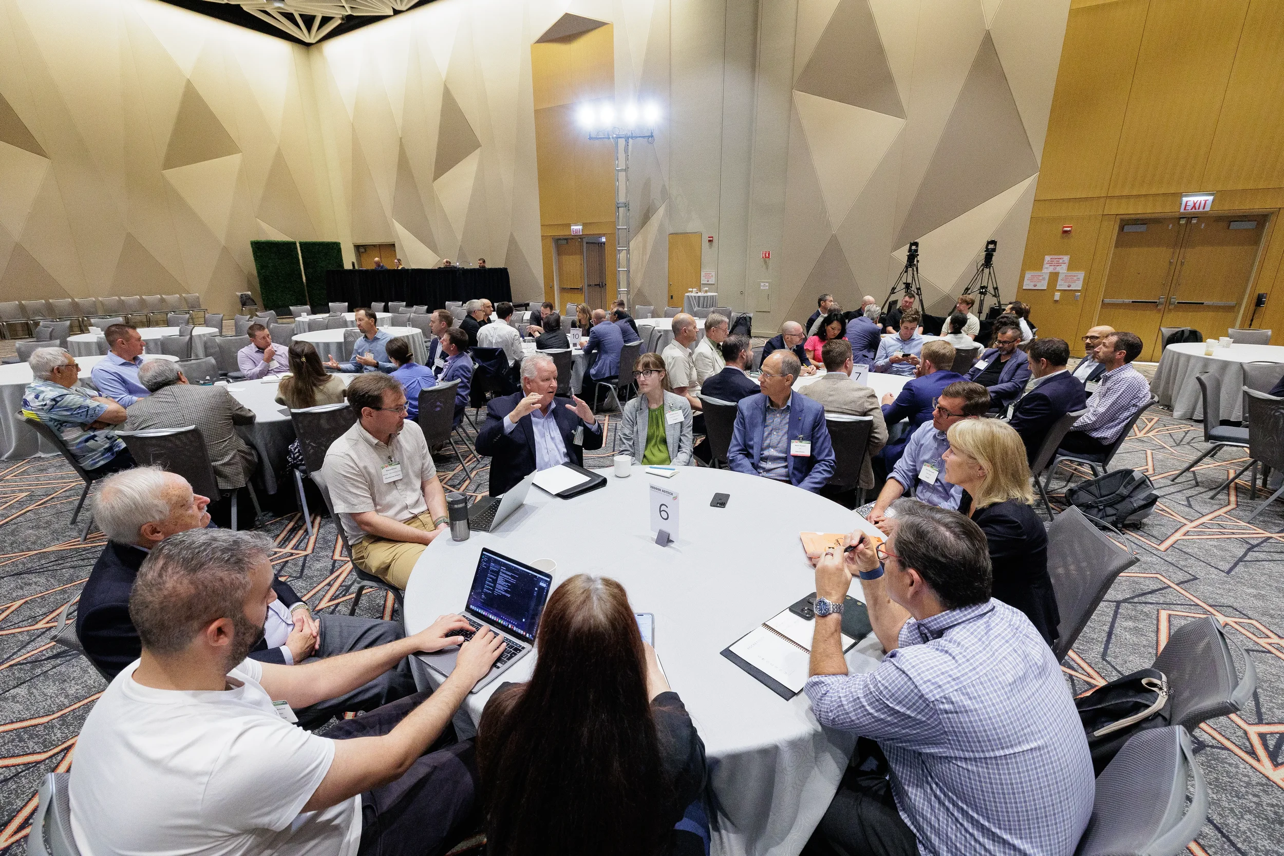 Attendees engage in small group discussion at numbered round tables filling ballroom at Orlando industry conference