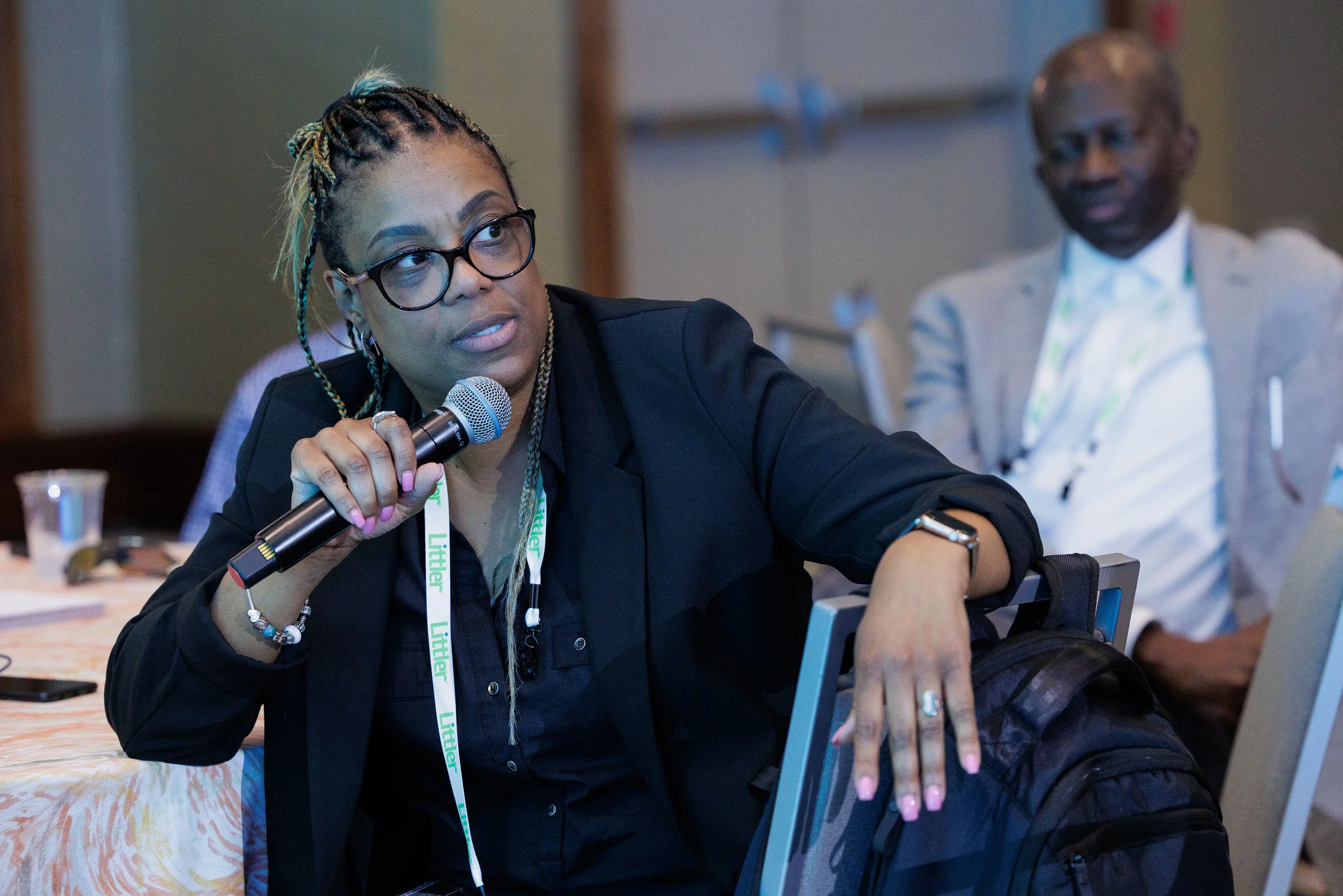 Female attendee with lanyard holds microphone while speaking during seated session at Orlando industry conference
