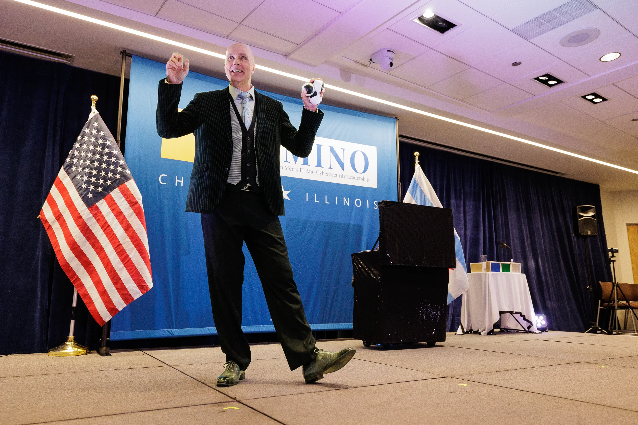 Entertainer juggles on stage in front of branded backdrop with flags at Orlando corporate conference event
