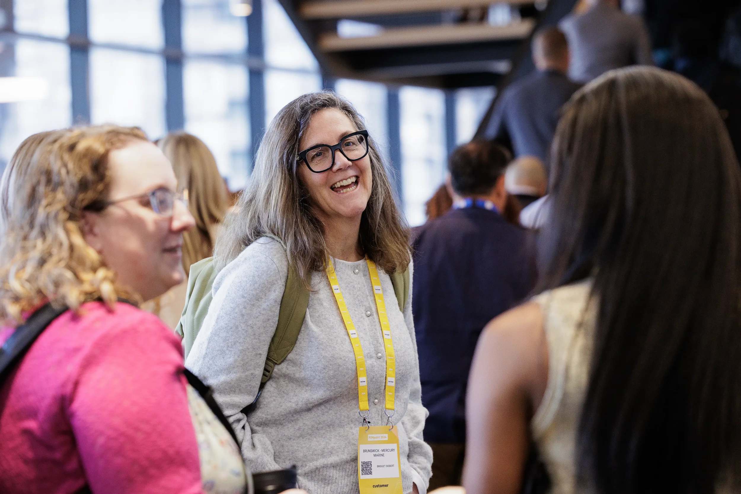 Smiling attendee with yellow lanyard chats with colleagues in lobby at Chicago corporate event