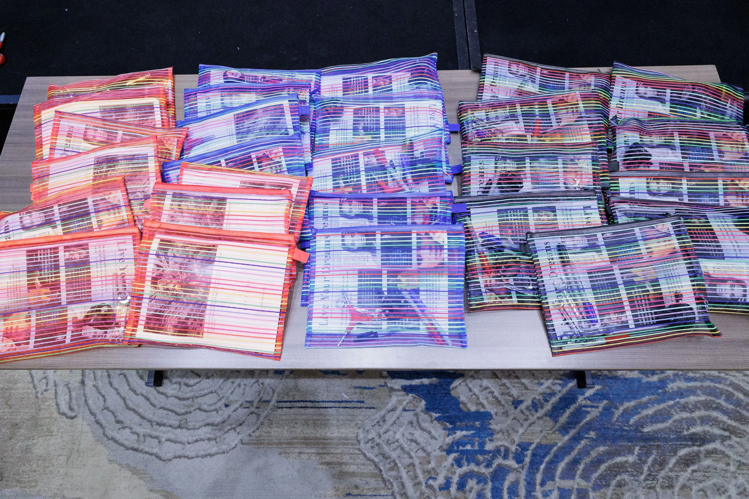 Colorful striped branded gift pouches arranged in rows on table at Orlando industry conference