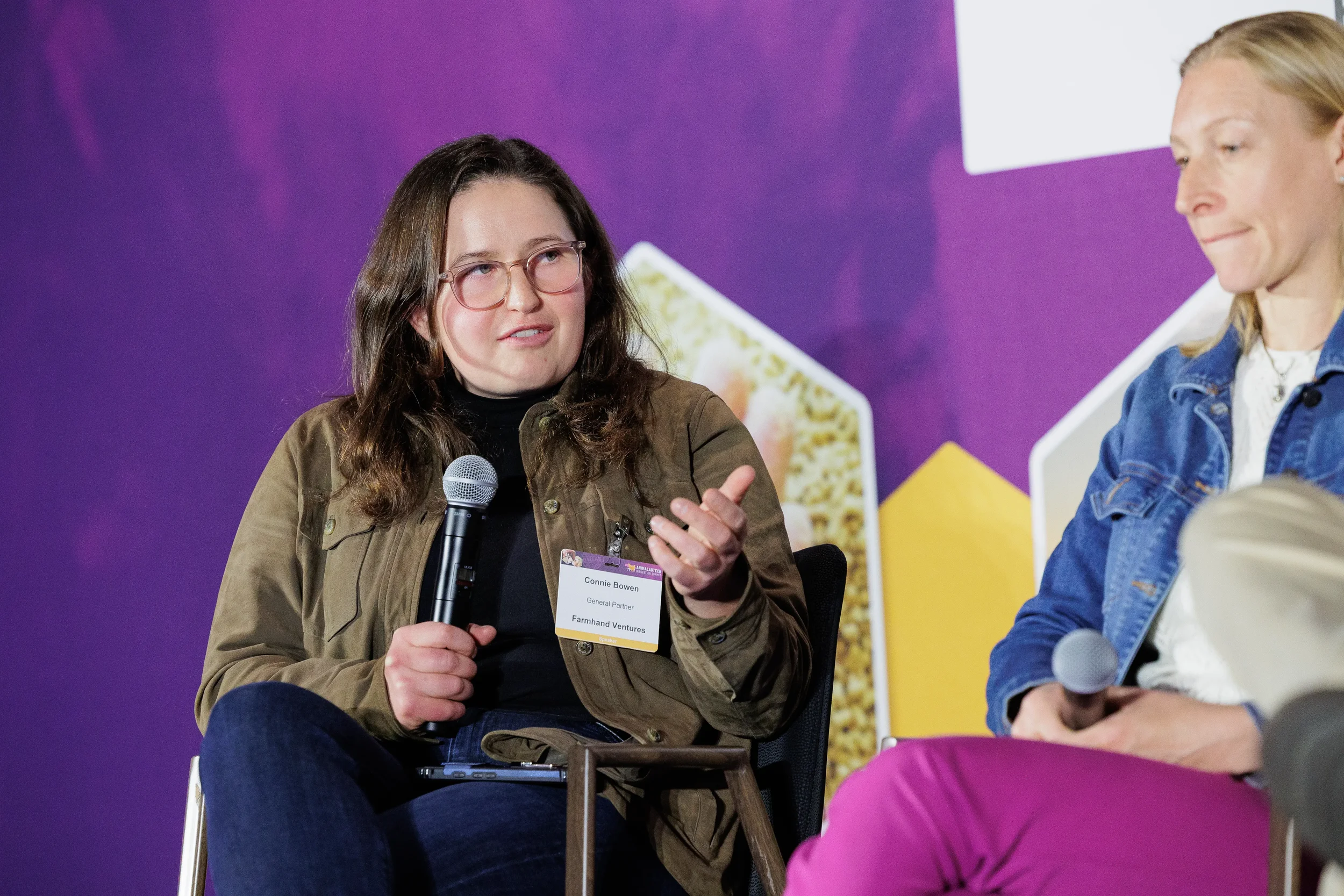Panelist gestures while speaking into microphone during seated discussion at Chicago industry conference
