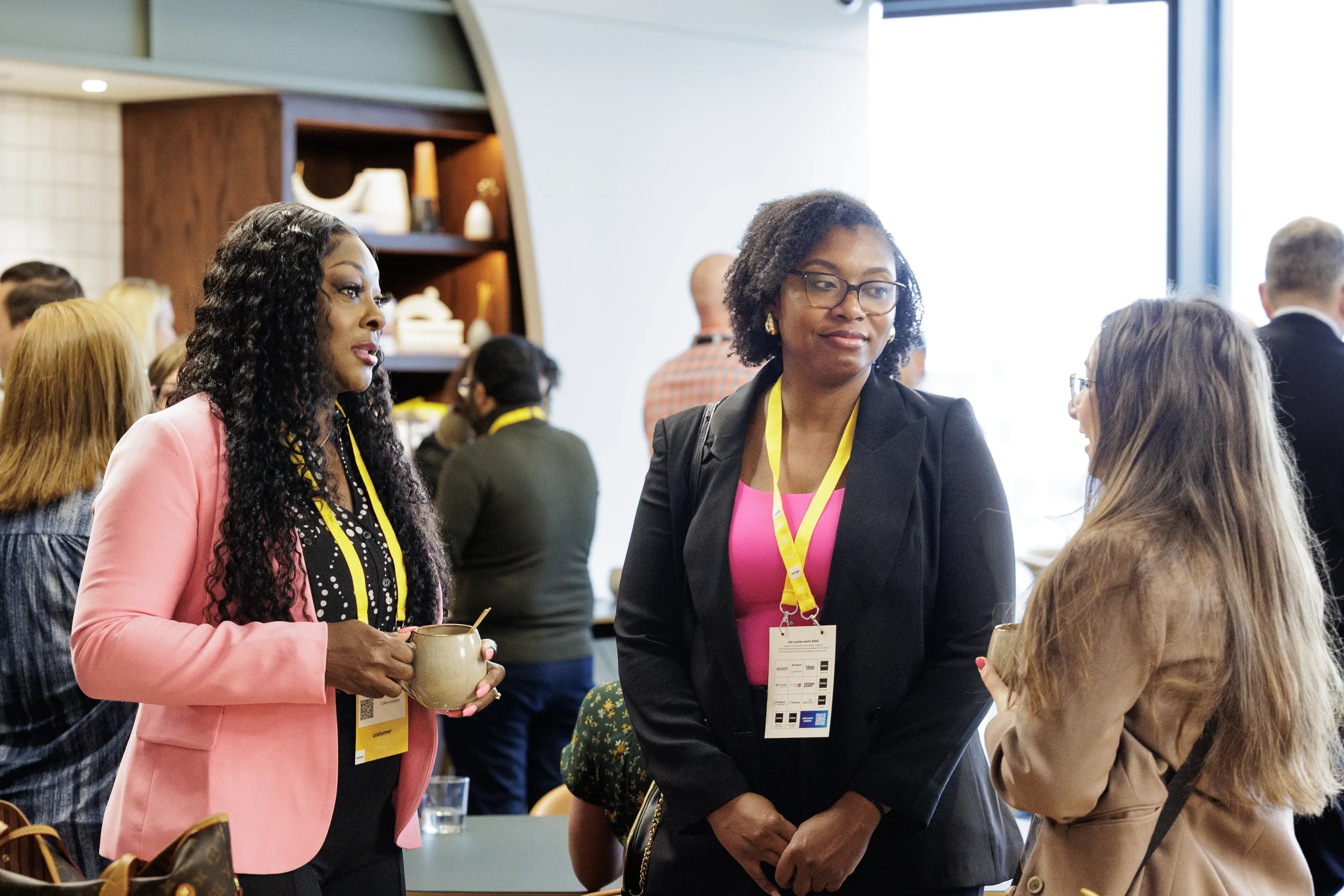 Attendees chat over coffee mugs with yellow lanyards during networking break at Orlando conference
