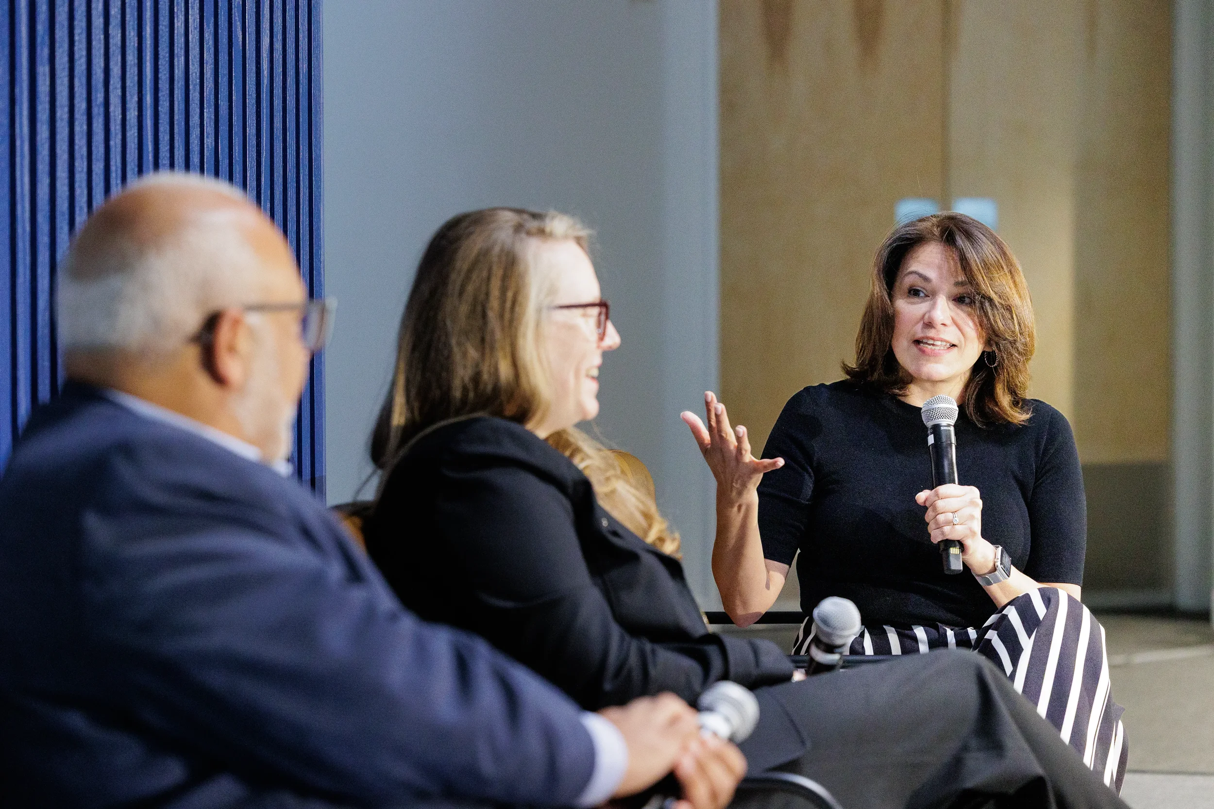 Panelist speaks into microphone while fellow speakers listen during discussion at Chicago event