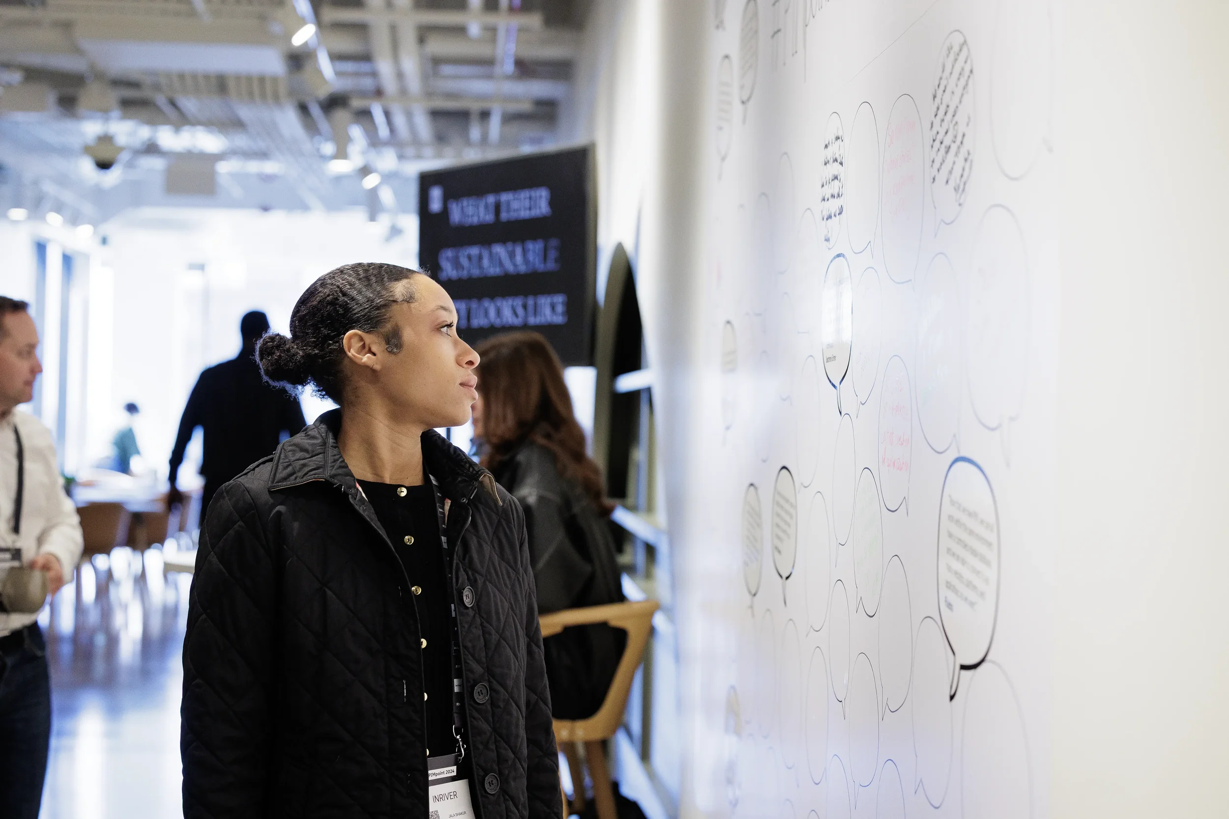 Attendee studies interactive speech bubble wall in corridor at Orlando industry conference