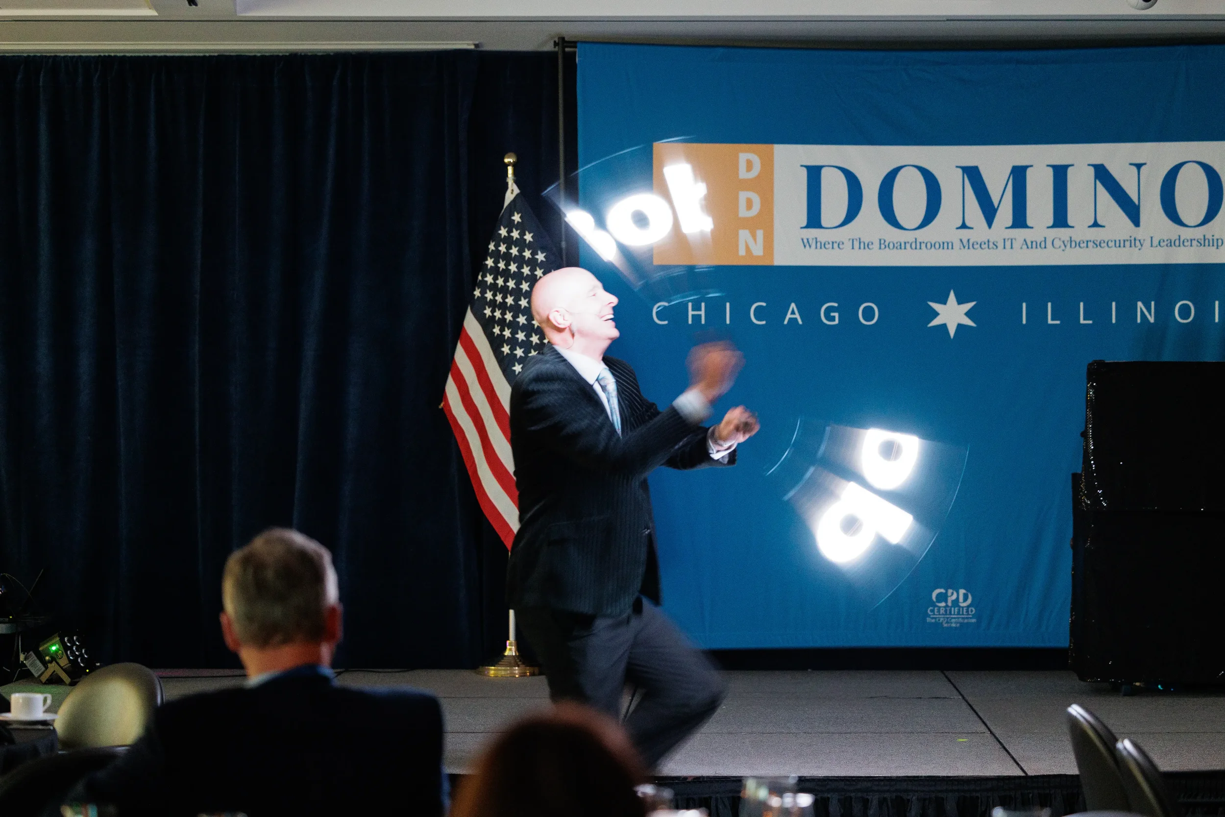 Entertainer spins glowing rings on stage in front of branded backdrop at Chicago corporate conference event