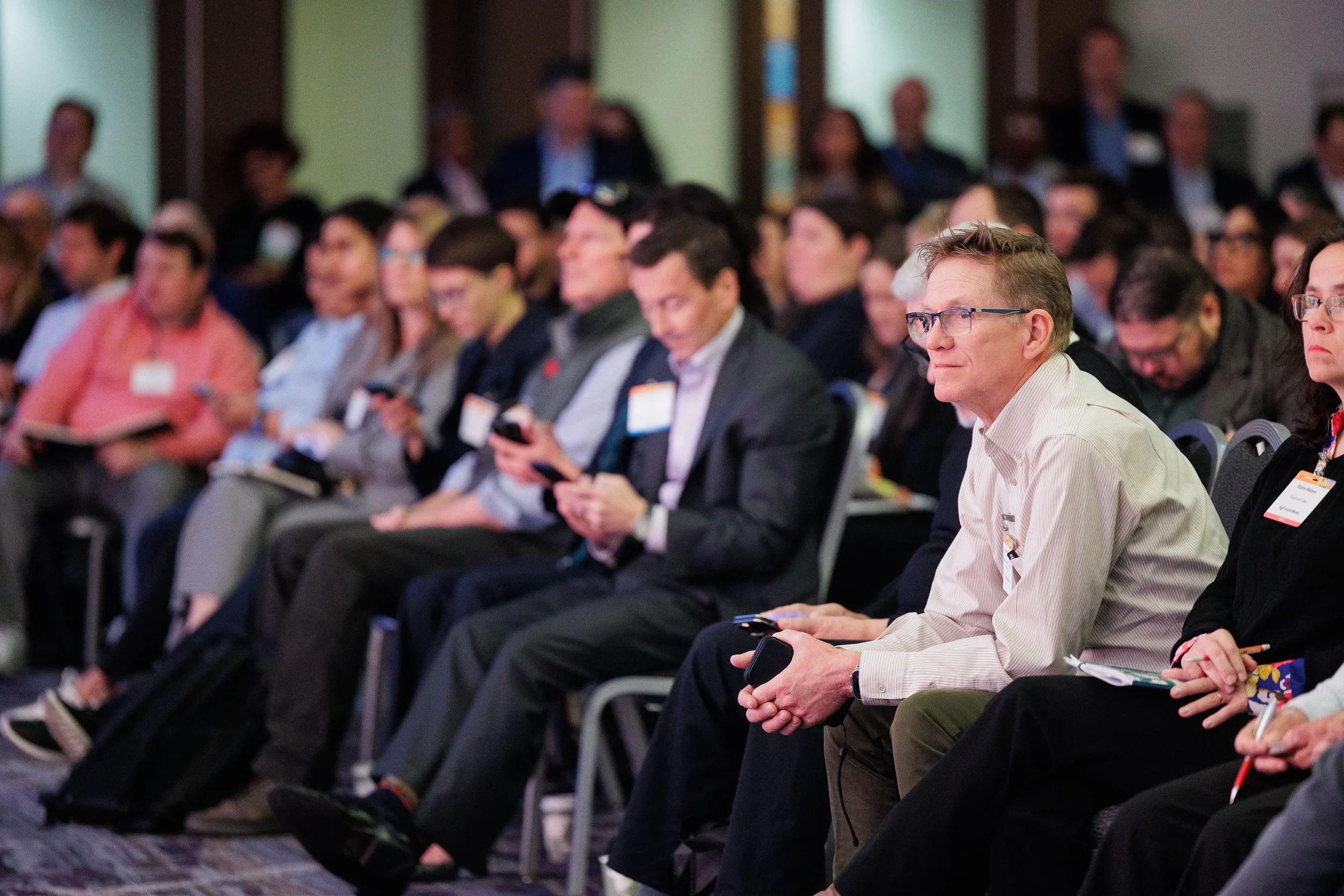 Rows of badged attendees seated and listening during breakout session at Orlando corporate conference