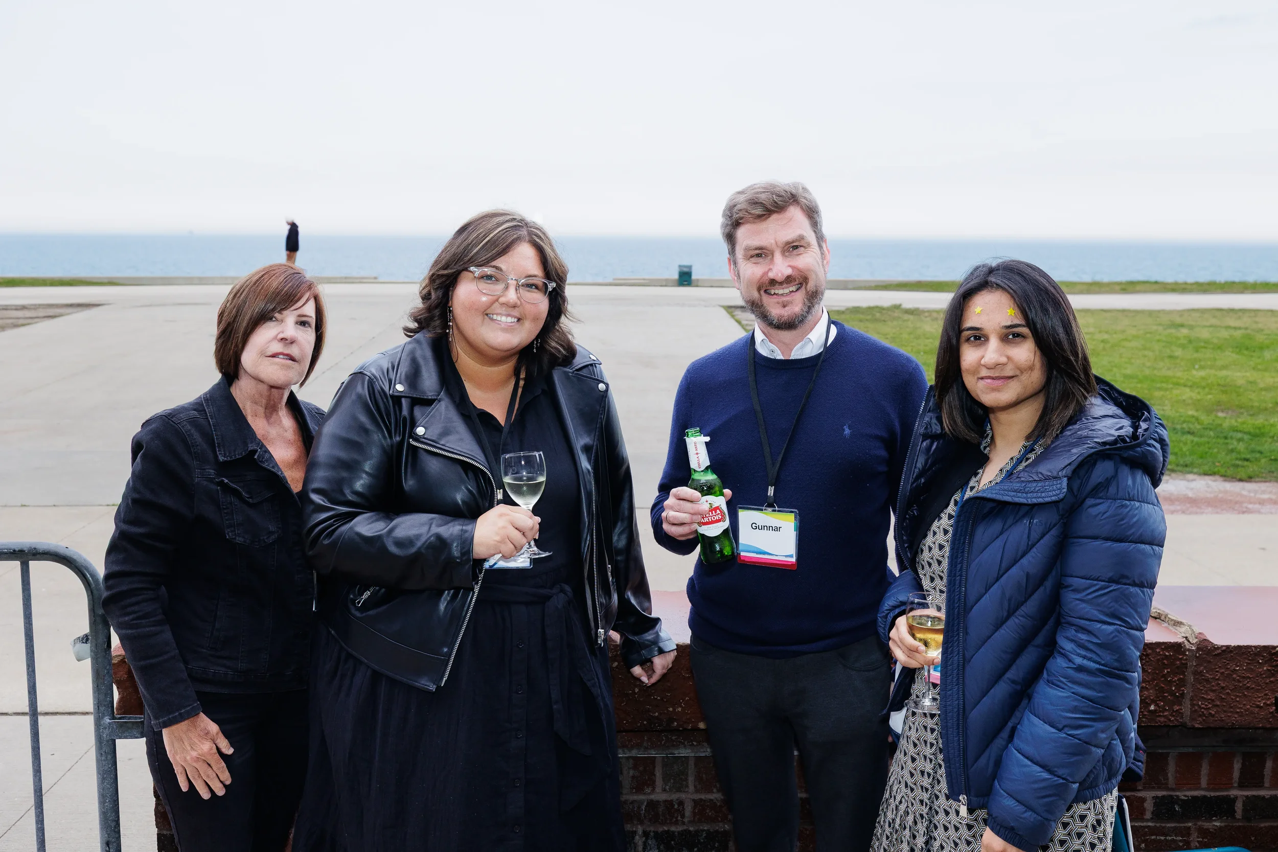 Four attendees pose with drinks at outdoor networking reception overlooking Chicago lakefront