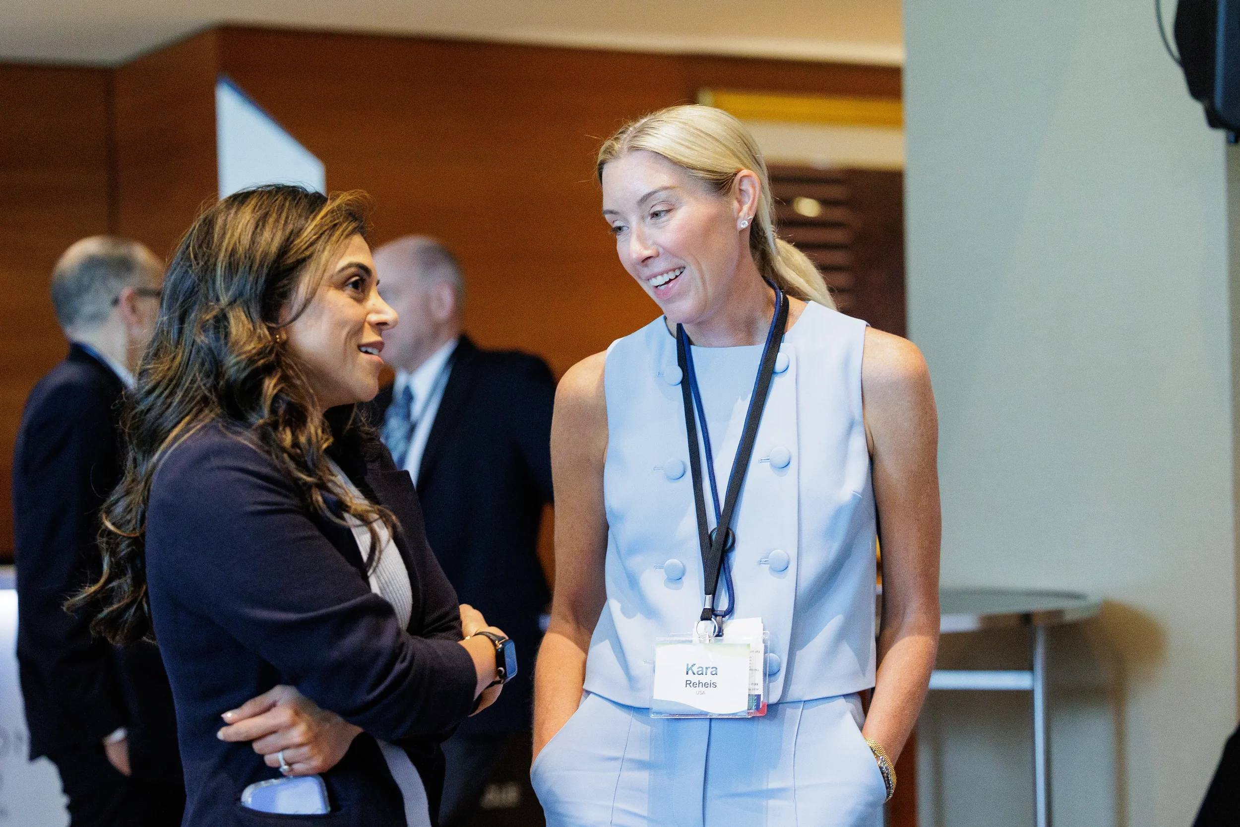 Attendees converse in hallway with name badges at Orlando corporate conference