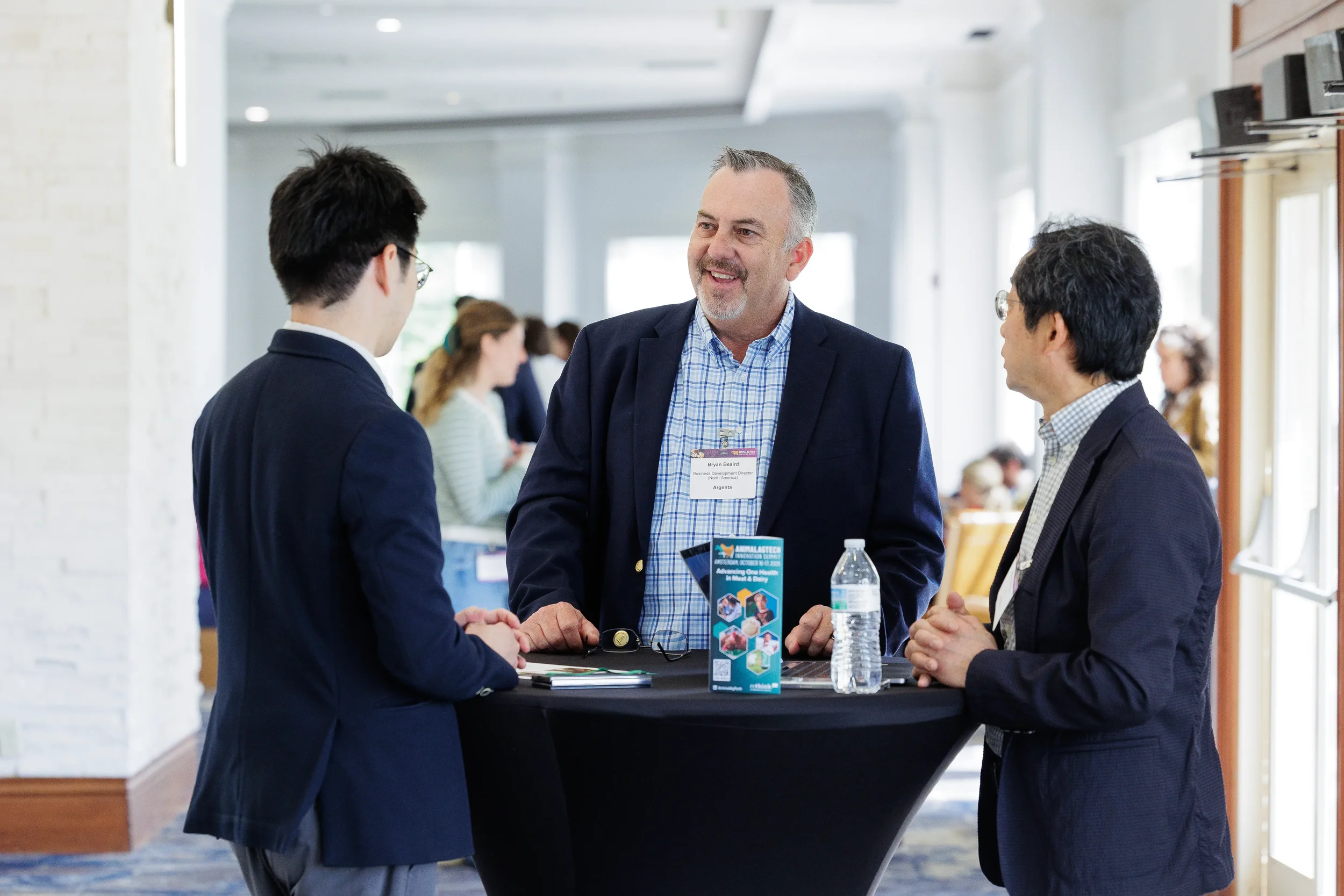 Three attendees converse around cocktail table during networking break at Chicago conference