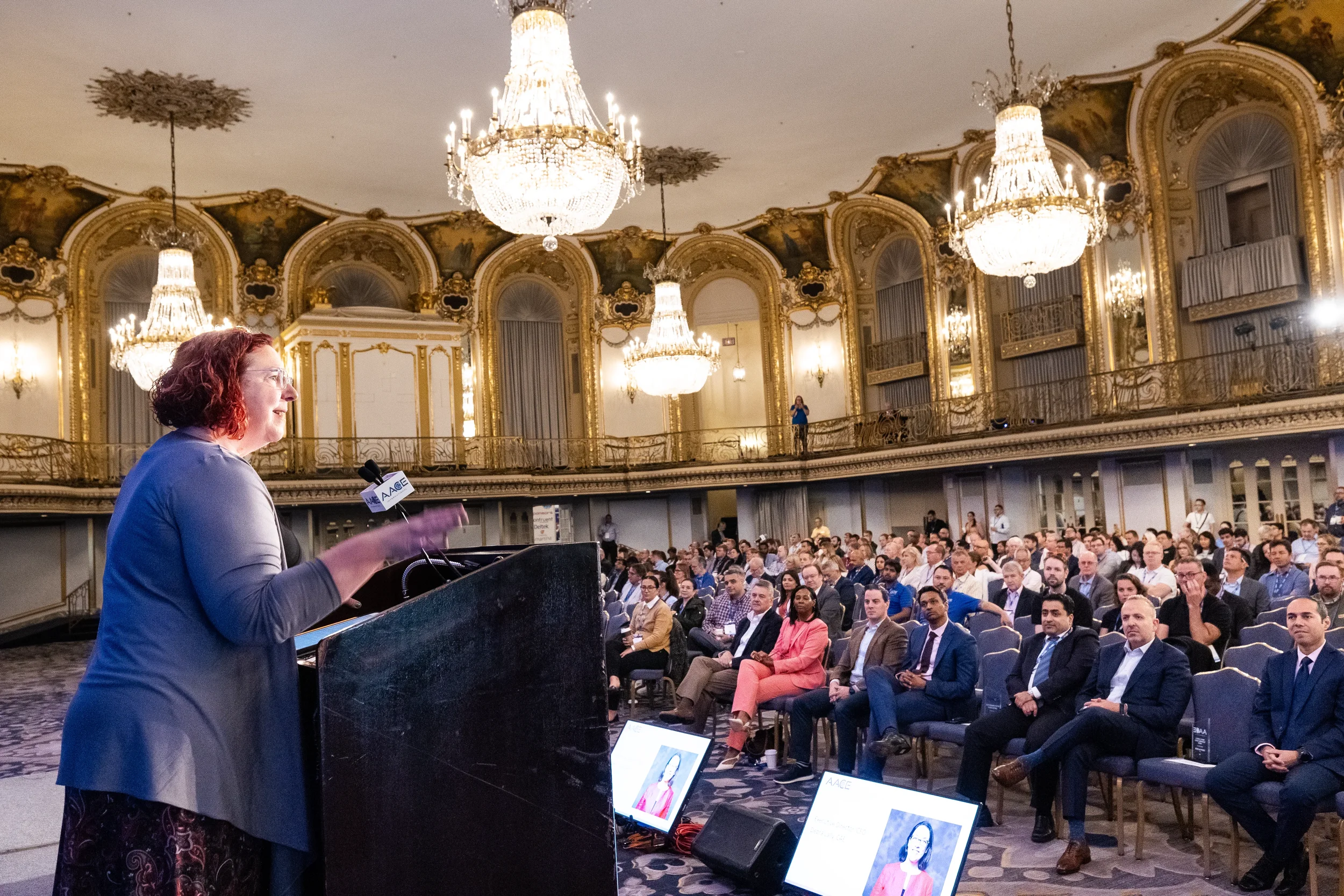 Keynote speaker addresses audience from podium in ornate Chicago Hilton ballroom at AACE International 2024