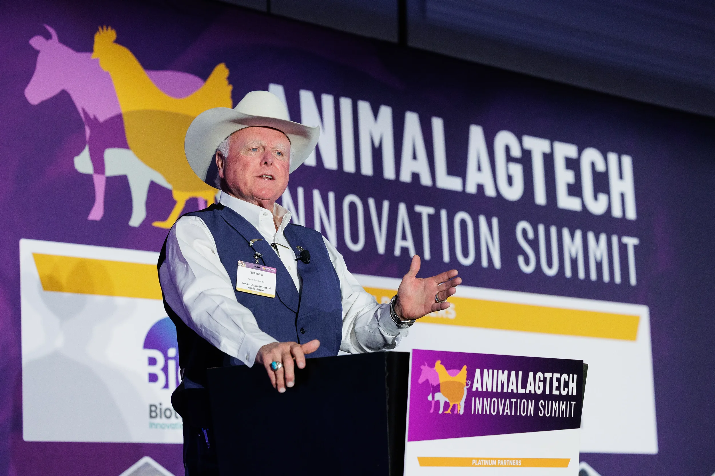 Speaker in cowboy hat gestures while addressing audience from podium at Orlando industry summit