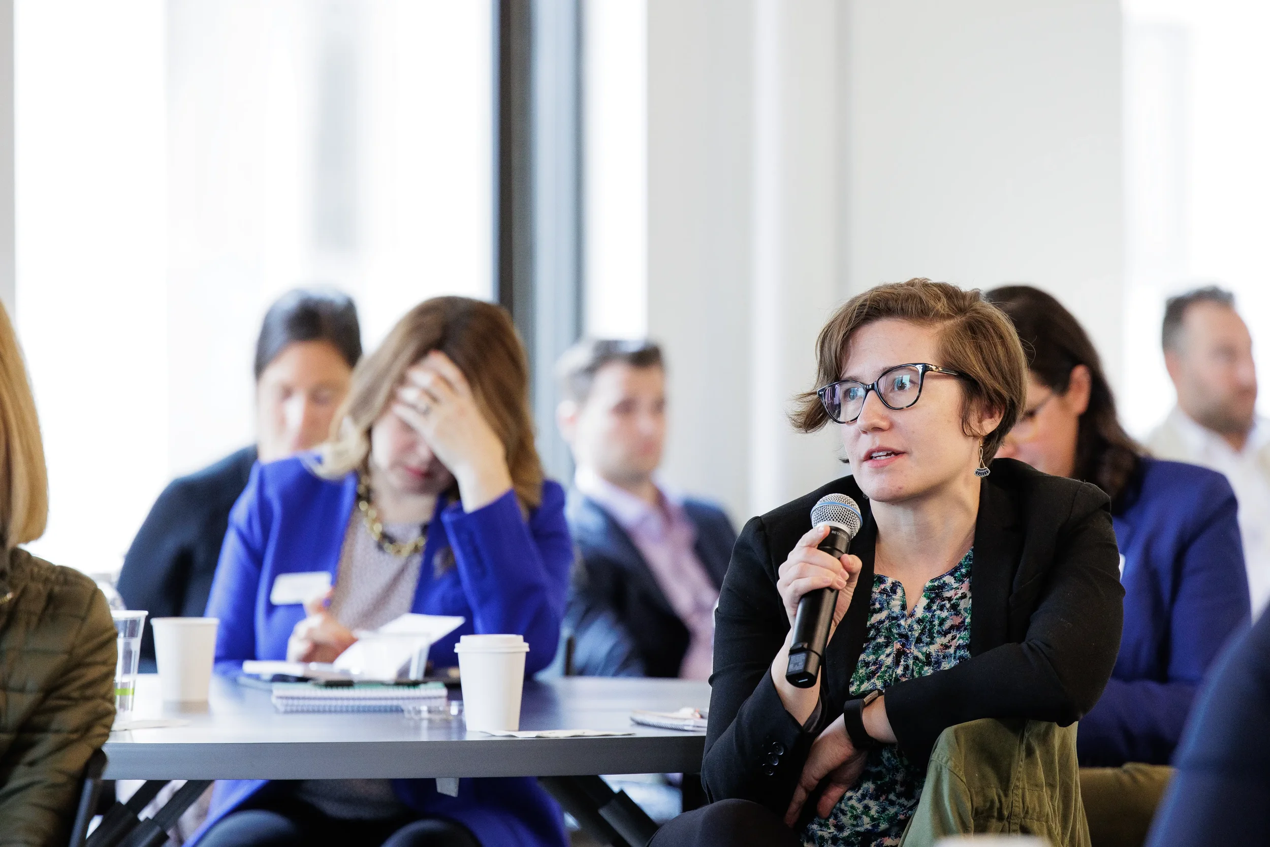 Seated attendee holds microphone to ask a question during a session at Orlando industry conference