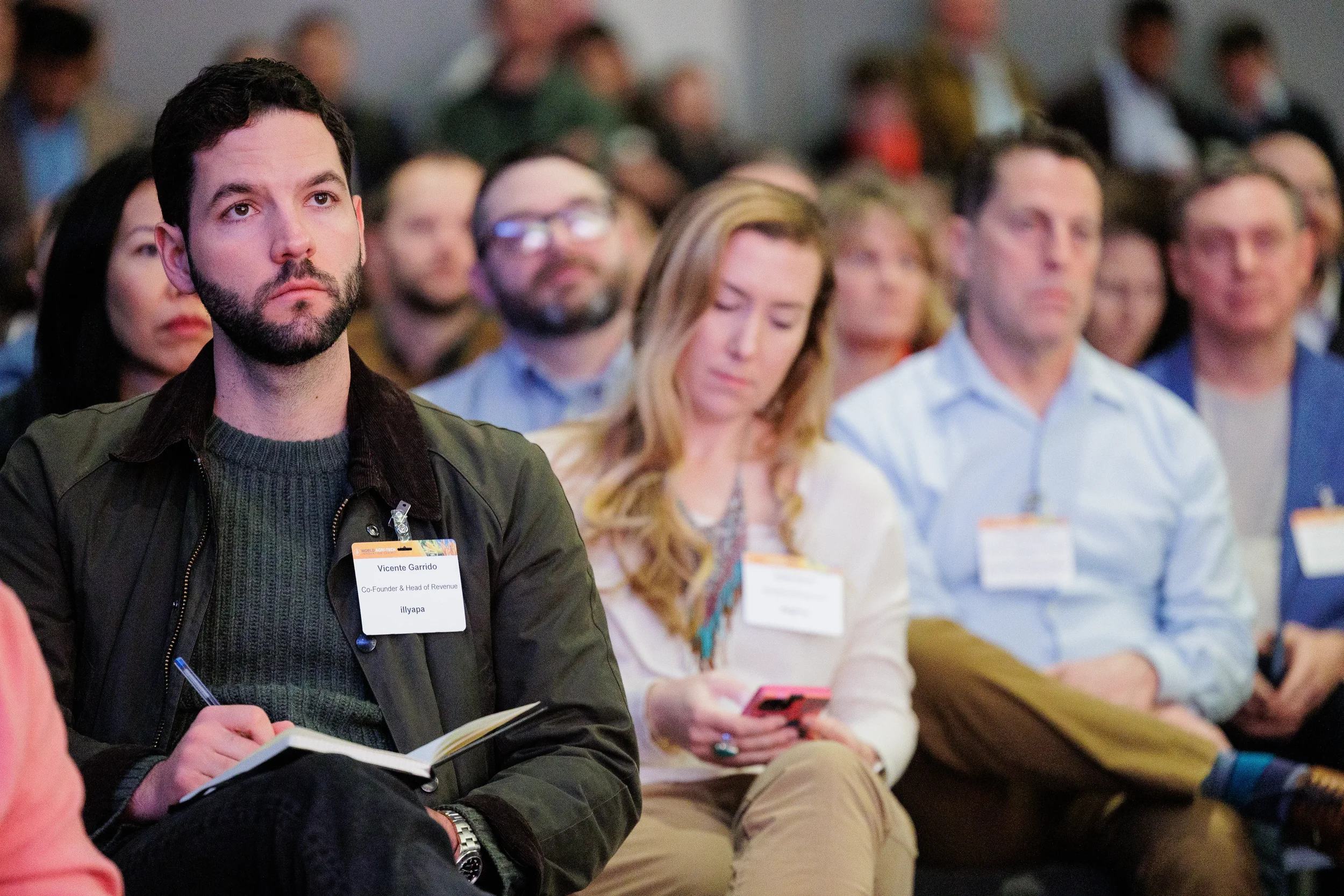 Rows of attendees with name badges listen attentively during session at Orlando corporate conference