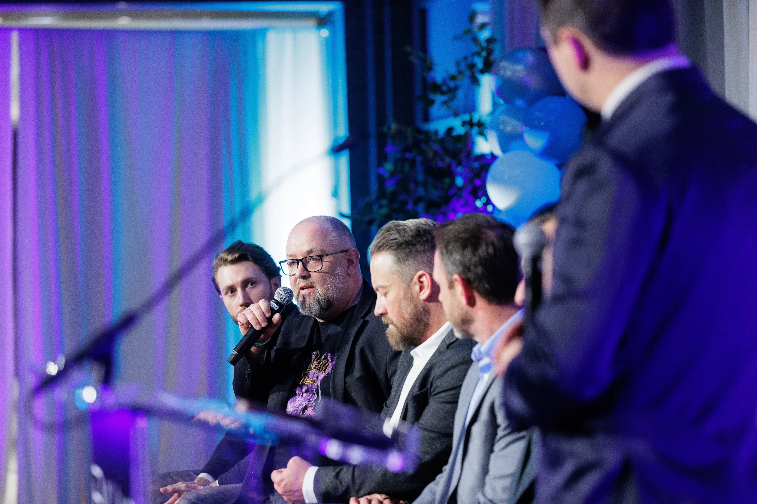 Panelist speaks into microphone while fellow panelists and moderator listen at Chicago conference