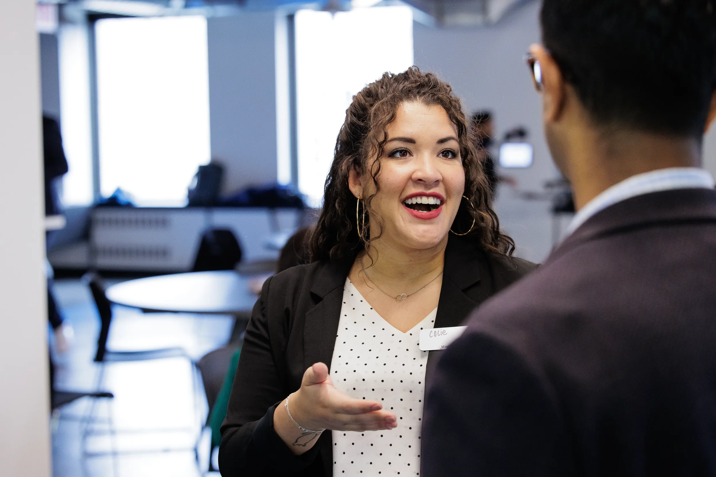 Female attendee gestures expressively while networking with another attendee at Chicago corporate event