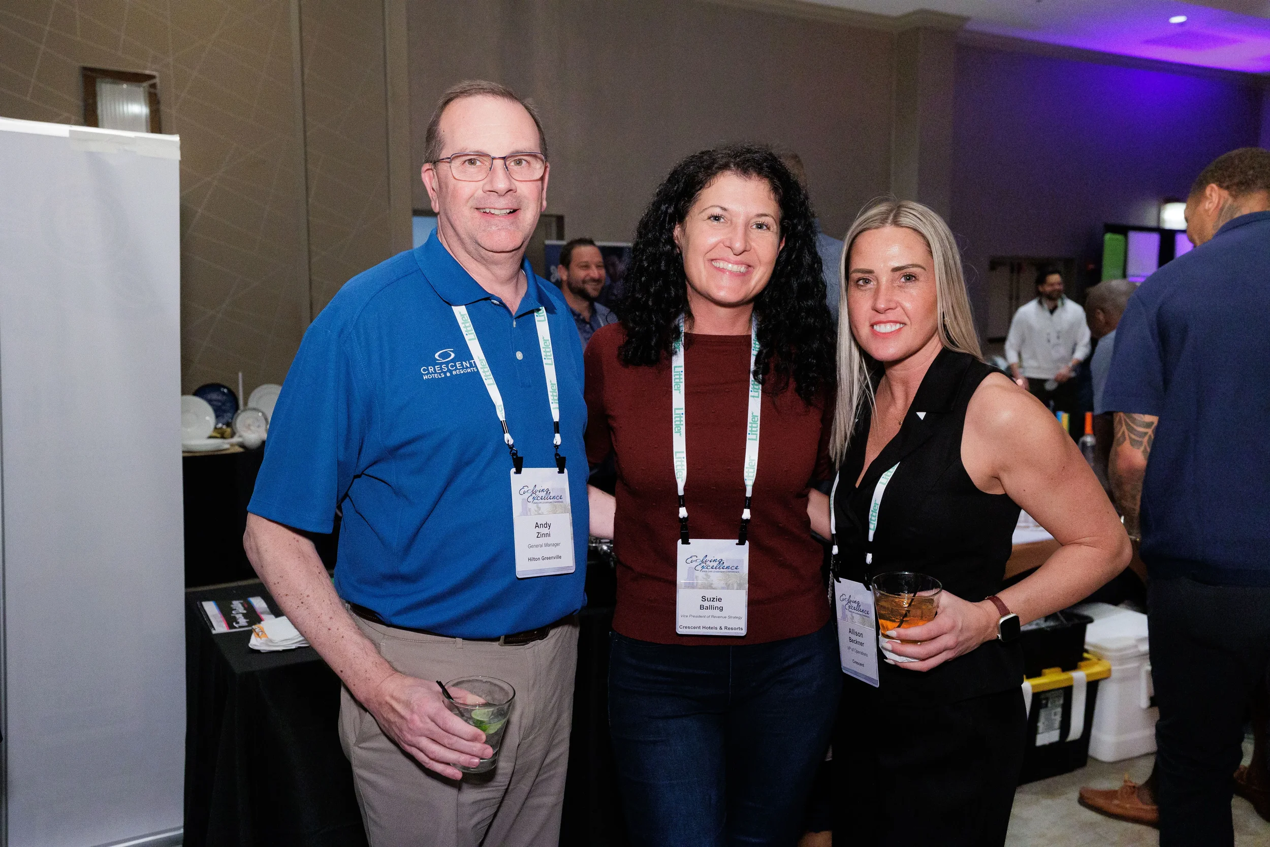 Three attendees with lanyards smile together at Chicago corporate conference networking reception