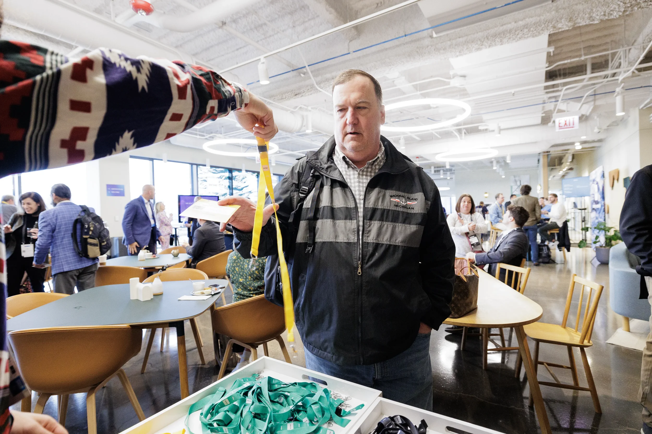 Registration staff hands yellow lanyard to arriving attendee in lounge at Chicago industry conference