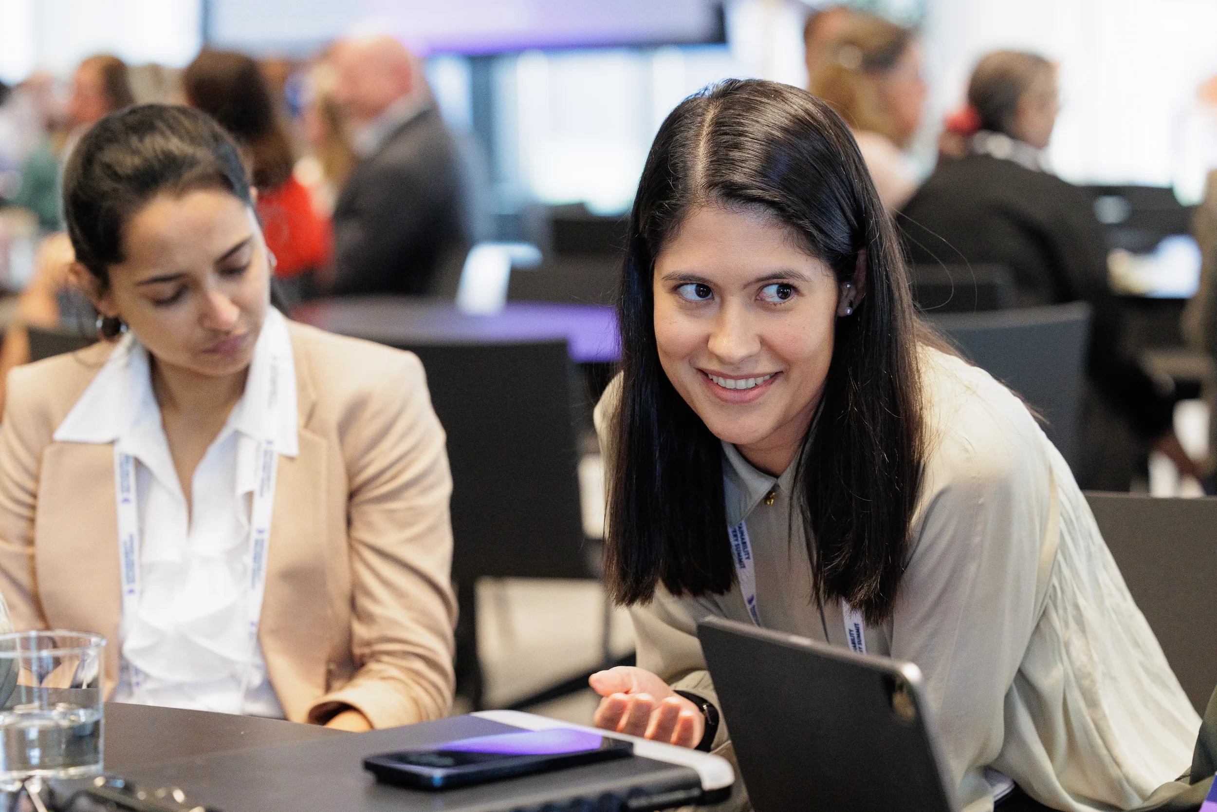 Attendees smile while conversing over laptop at Orlando industry conference session