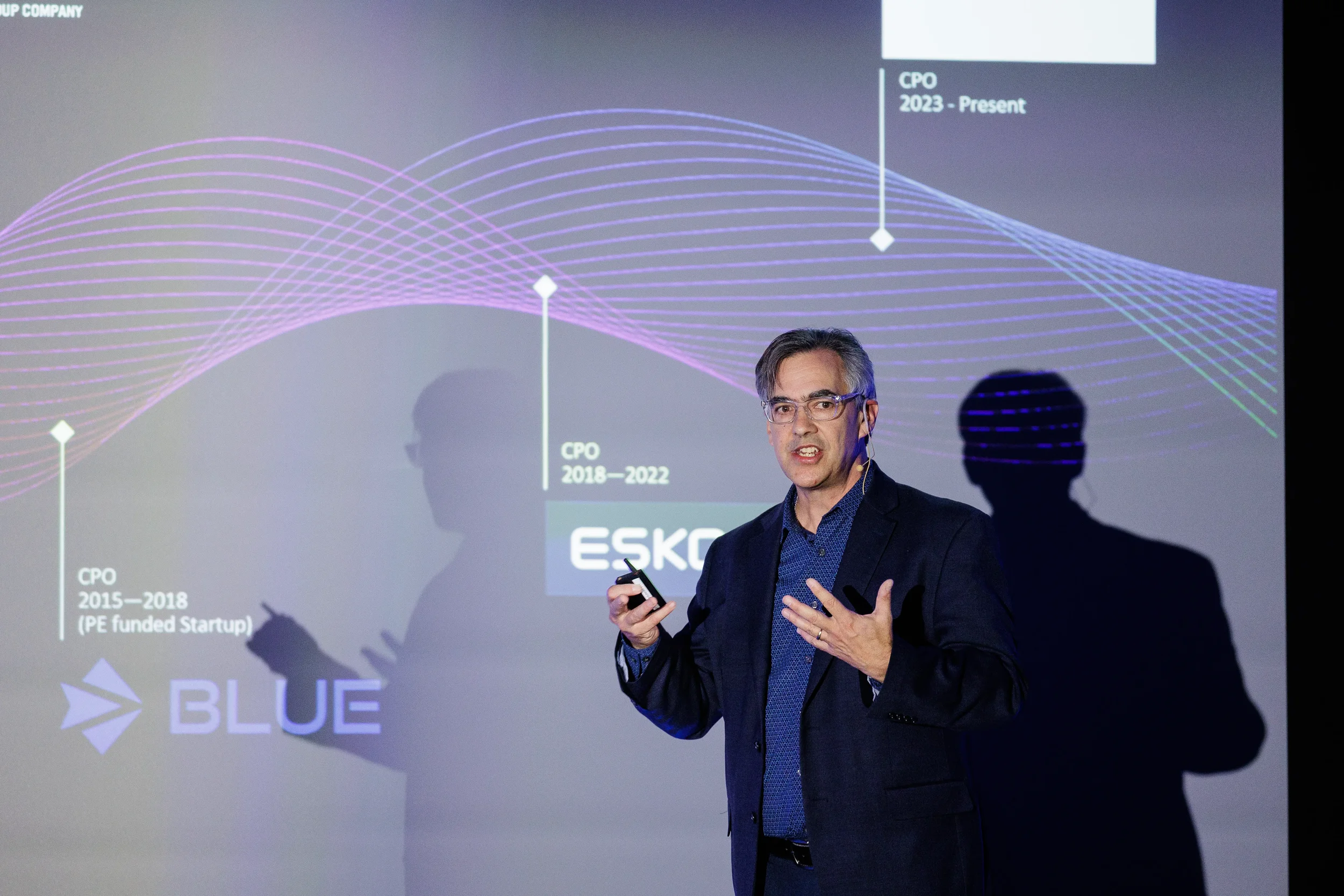 Speaker gestures in front of career timeline slide on stage at Chicago industry conference