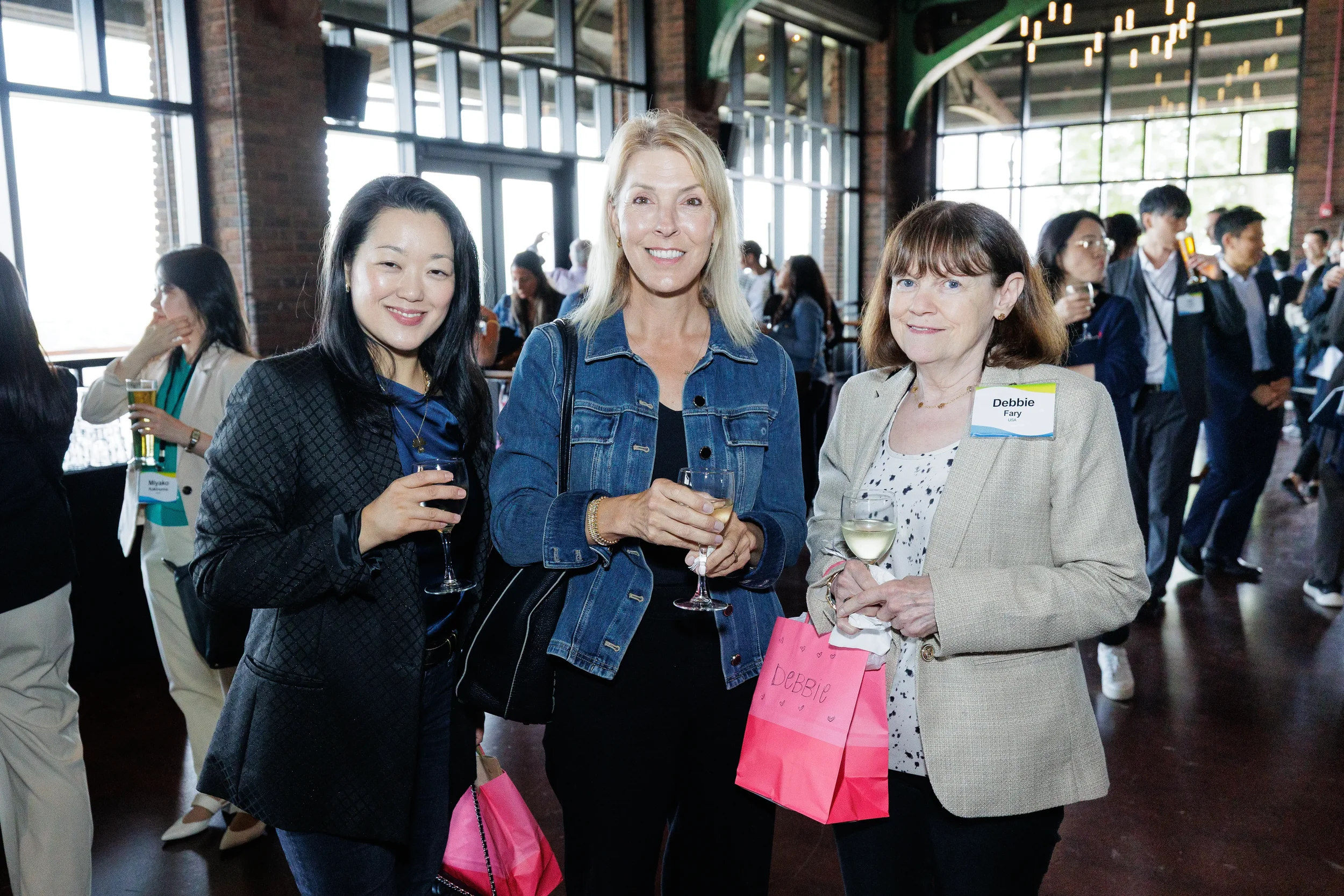 Three attendees pose with wine glasses at networking reception in brick venue during Orlando corporate event