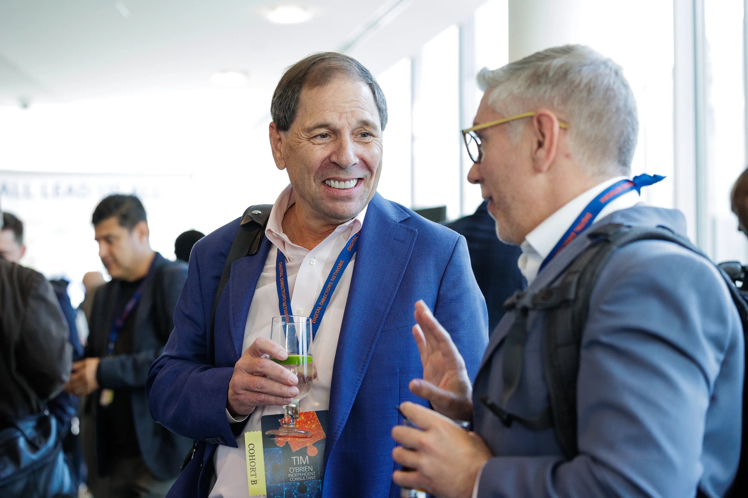 Two male attendees with lanyards laugh together over drinks during Orlando industry conference networking