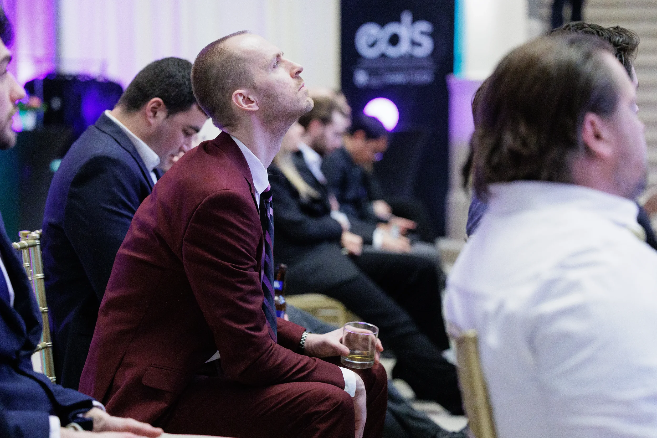Attendee in burgundy suit looks up attentively at presentation during Chicago corporate event